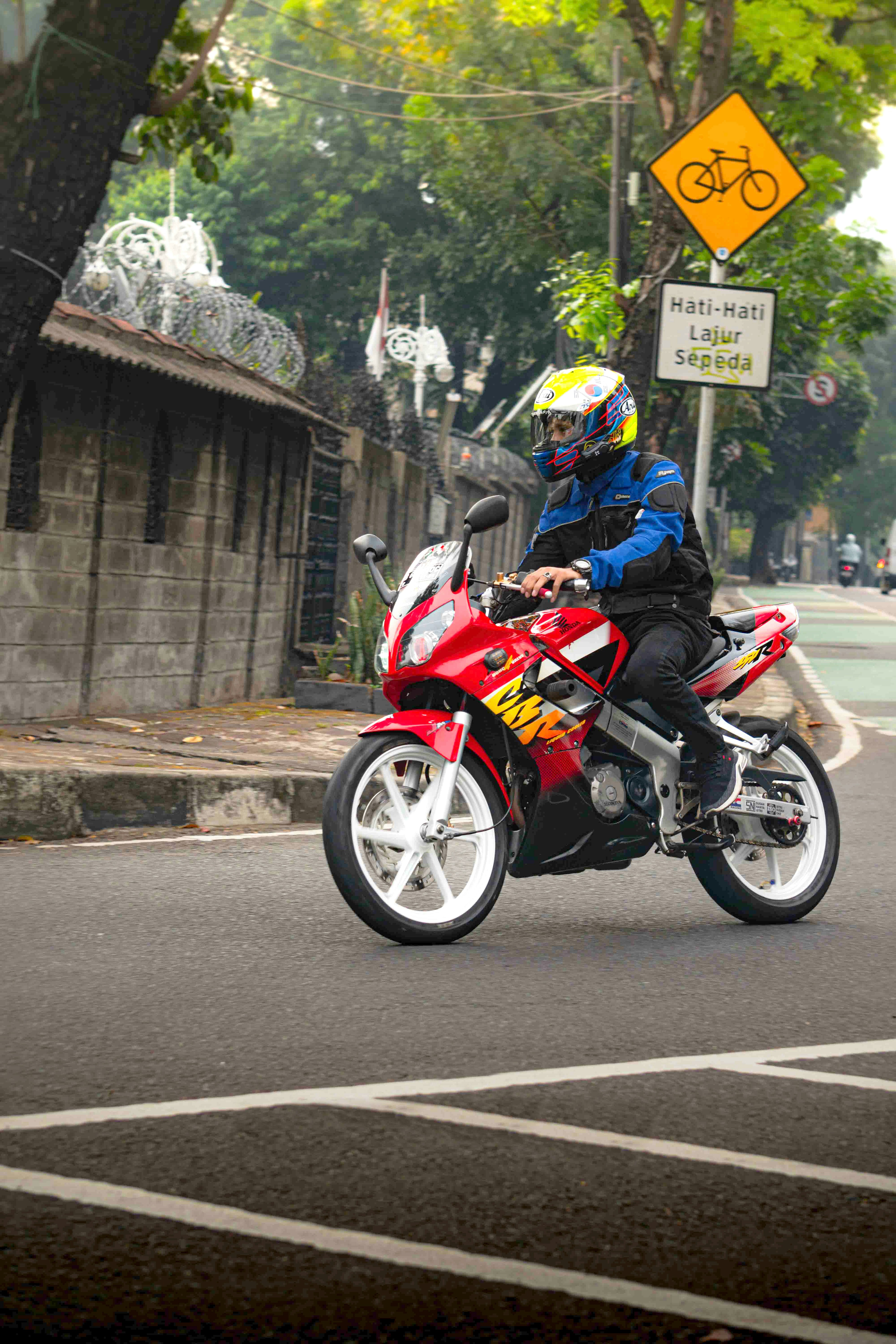 A man riding a red motorcycle down a street