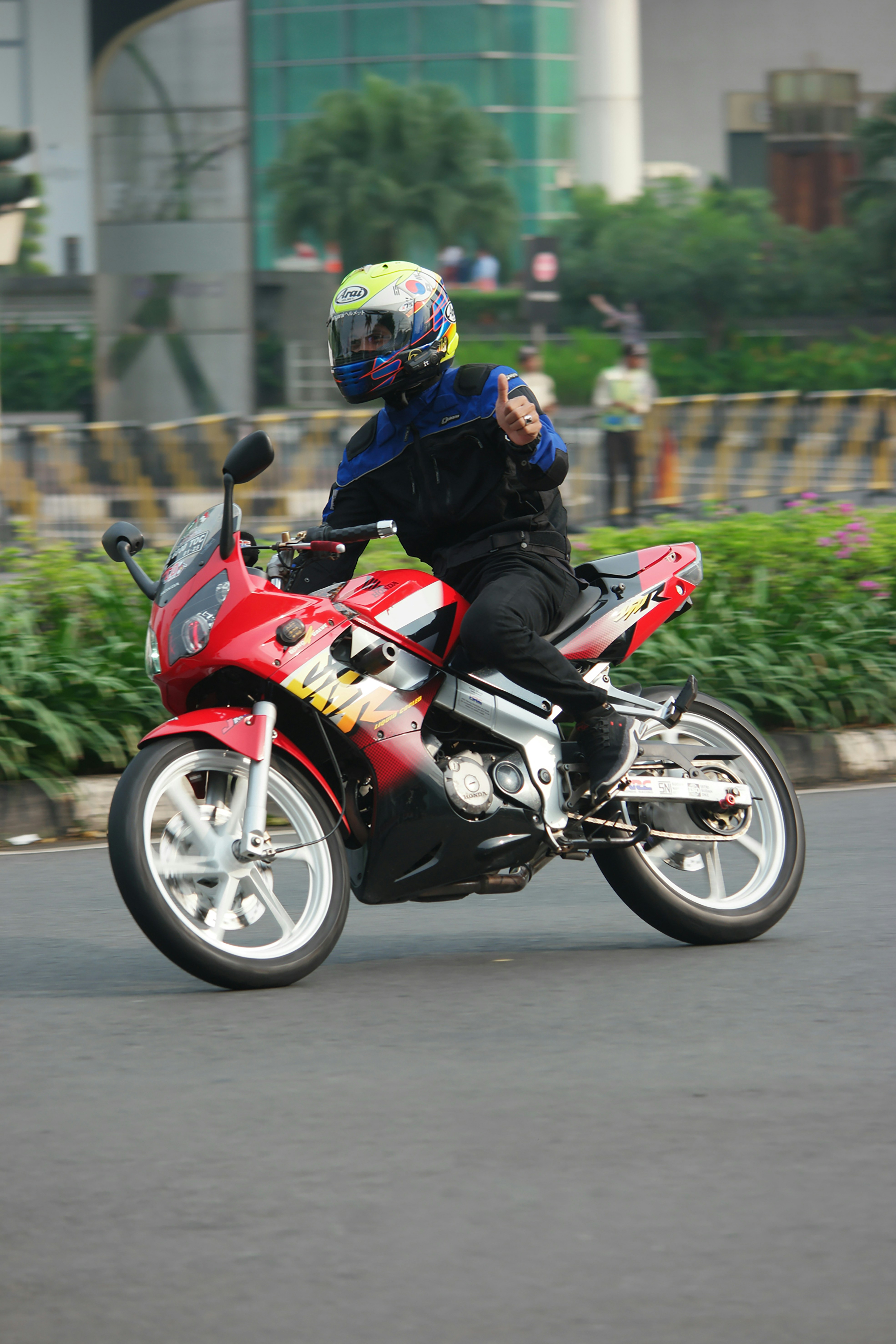 A man riding a red motorcycle down a street