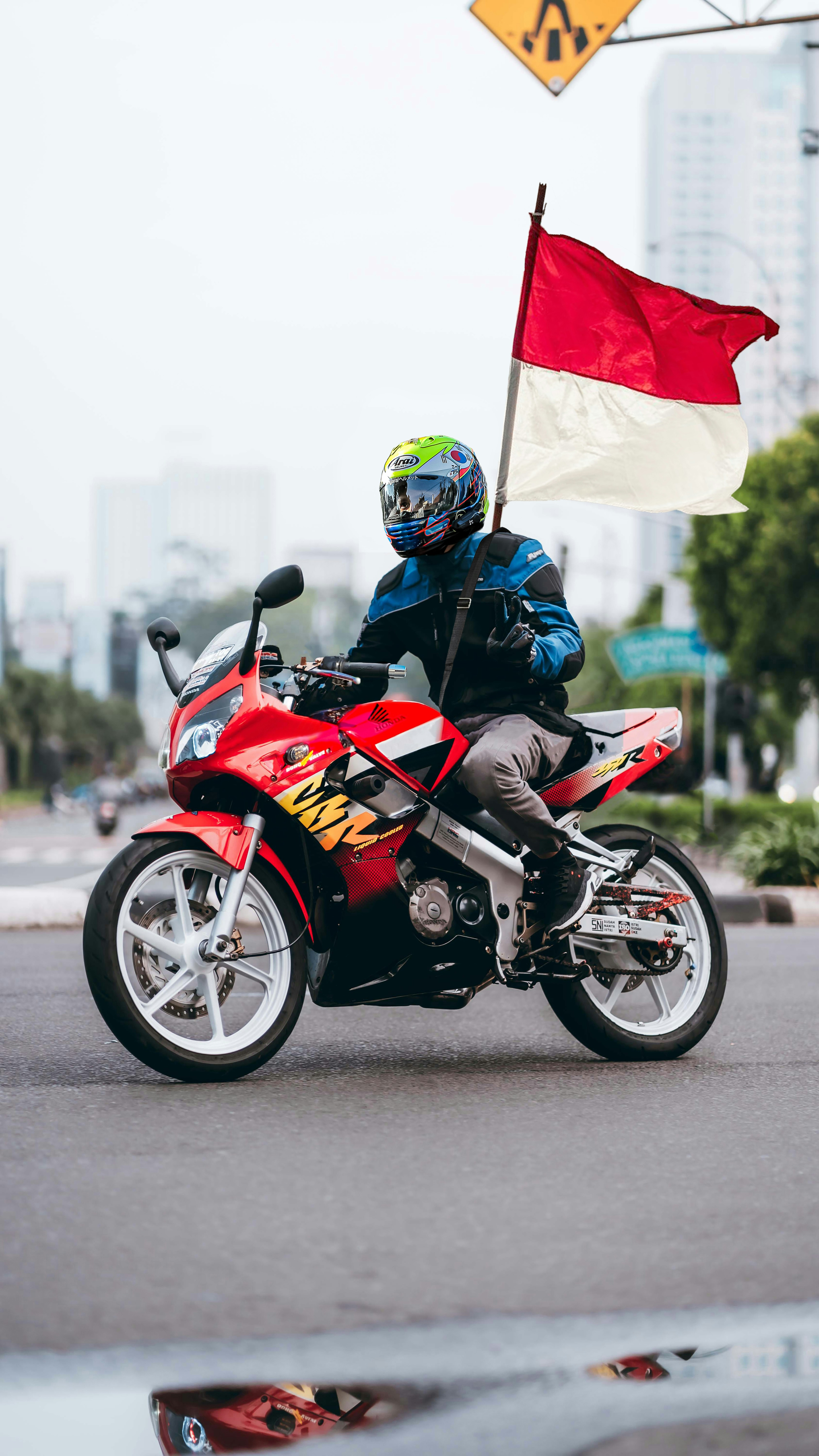 A man riding a red motorcycle down a street