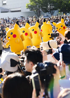 A large crowd of people with pokemon balloons in the shape of pikachu