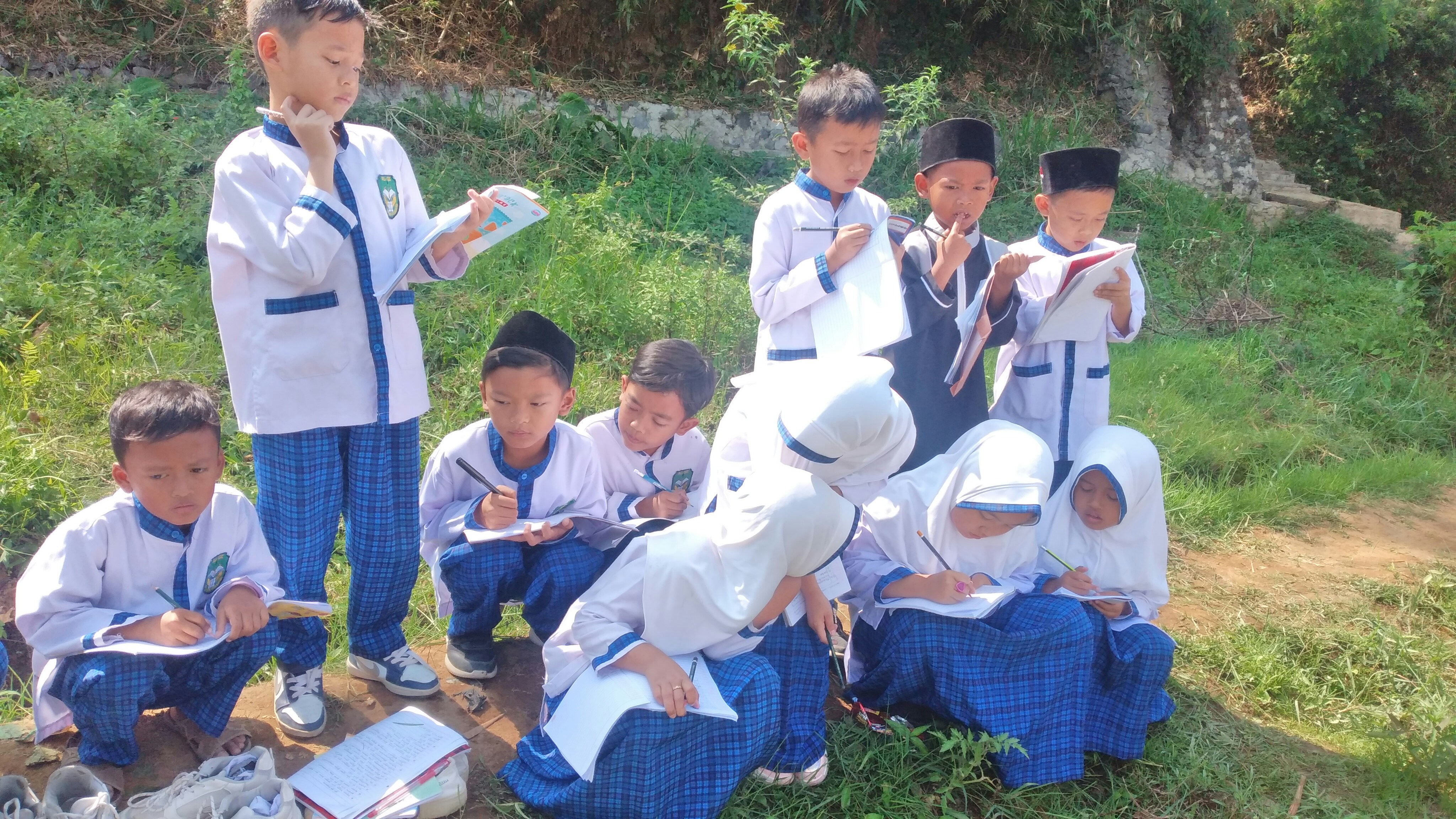 Children studying outdoors in a sunlit open area, focused and engaged in learning