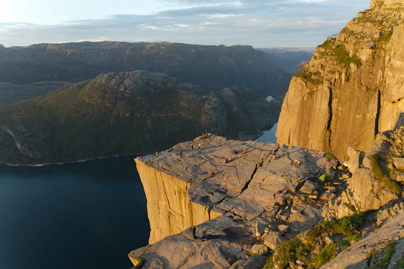 A man standing on top of a cliff next to a body of water