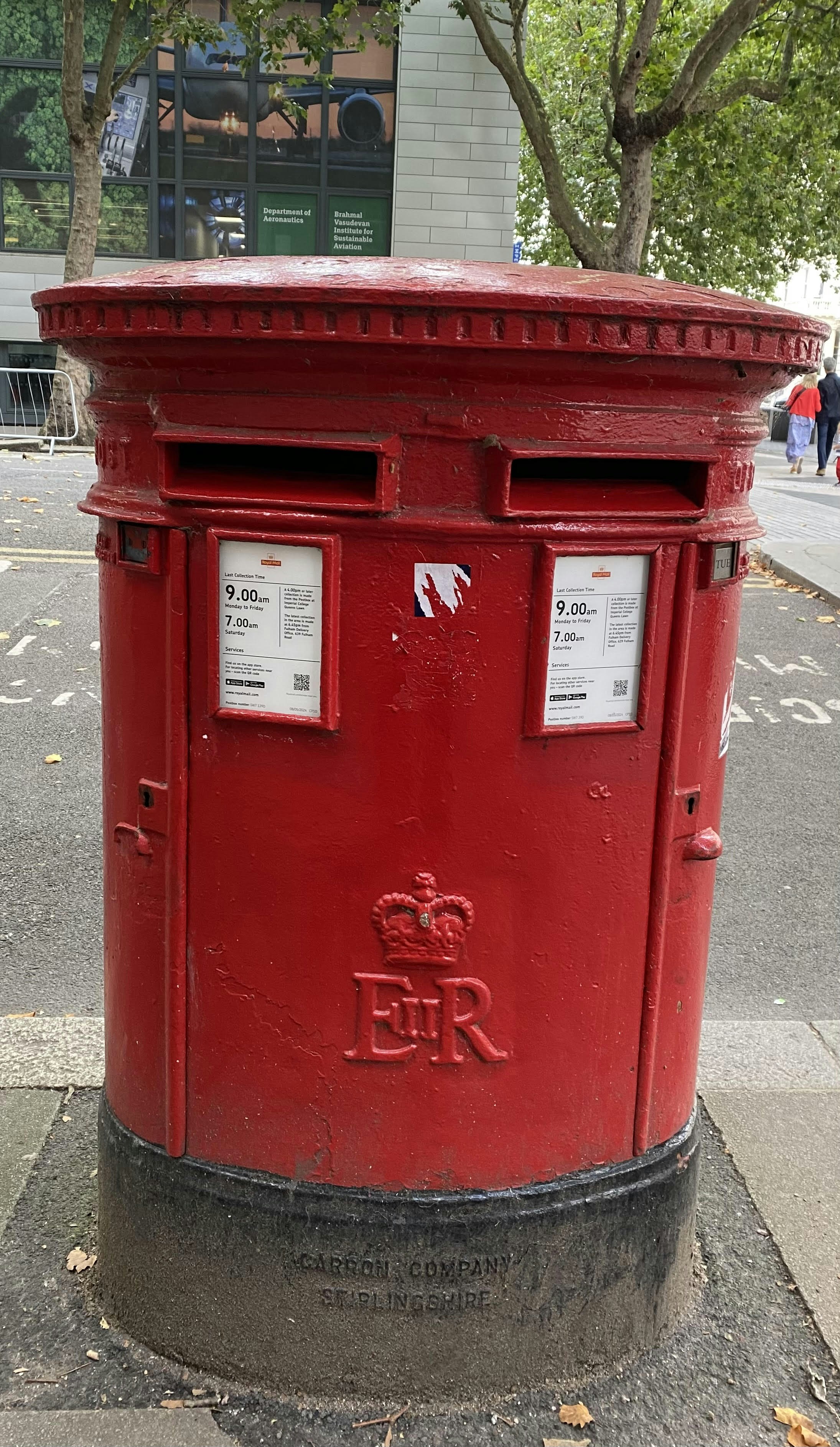 A red post box sitting on the side of a road