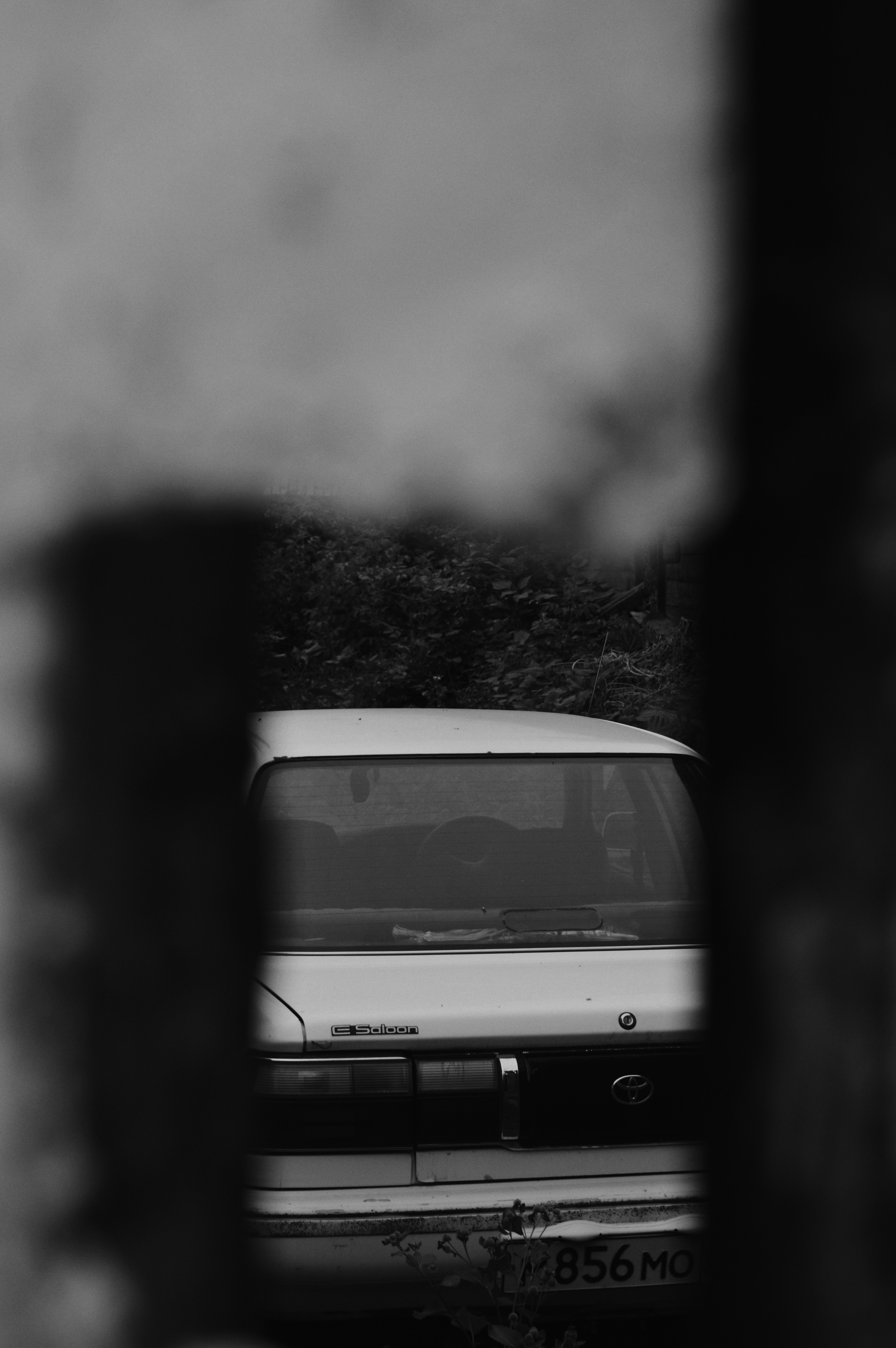 A car is seen through a hole in a wall