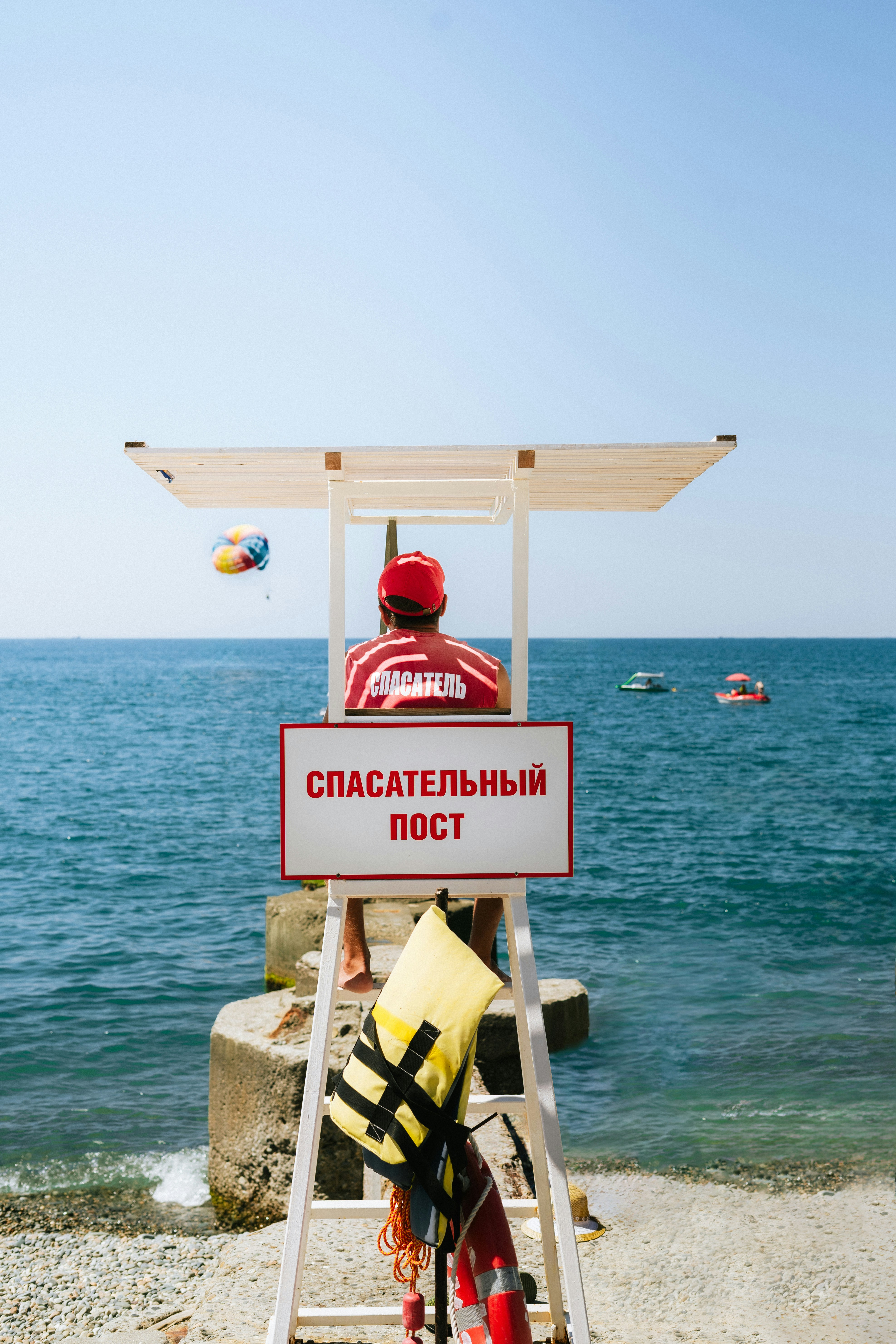 A man sitting on a lifeguard chair on the beach