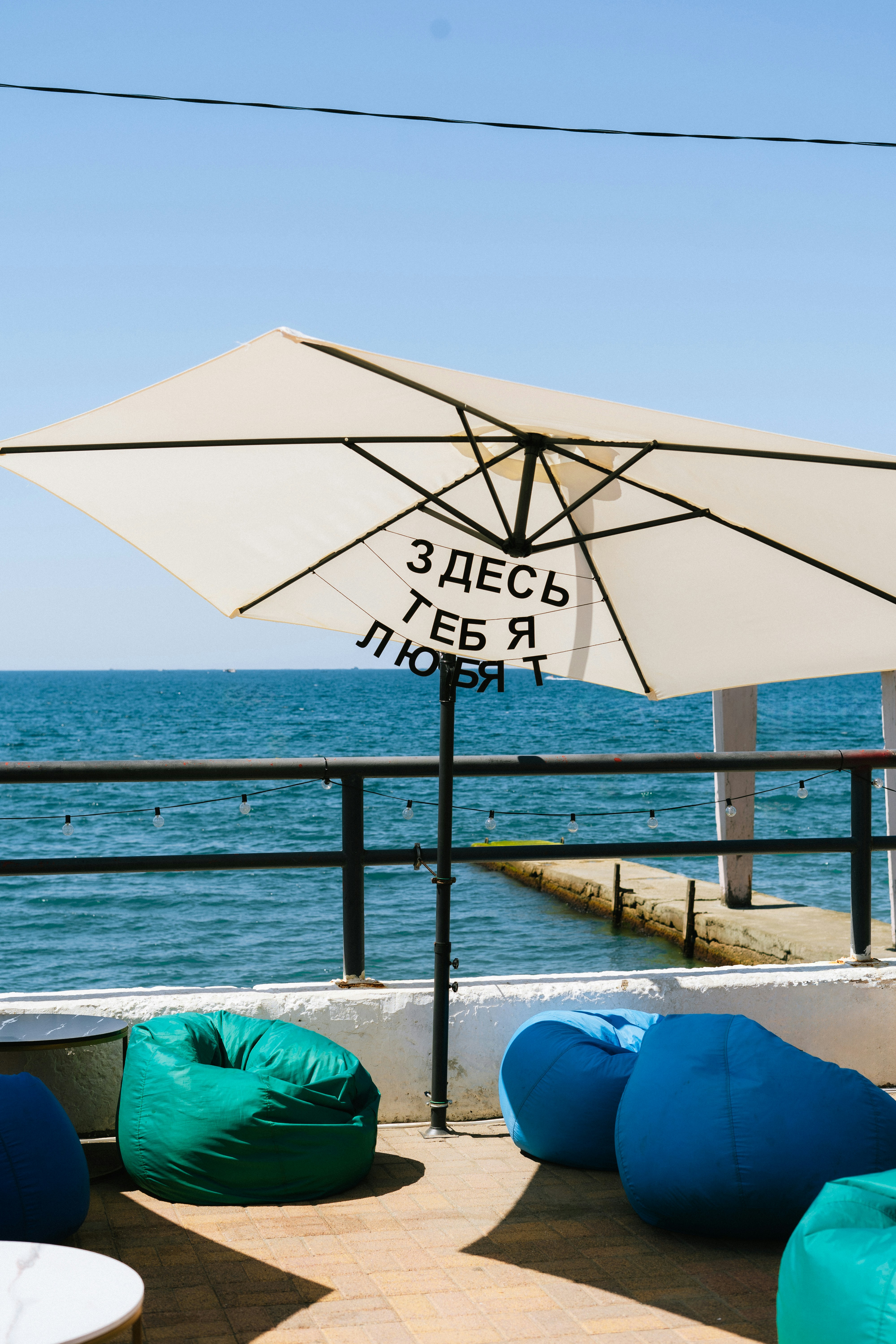 An umbrella and bean bag chairs on a deck overlooking the ocean