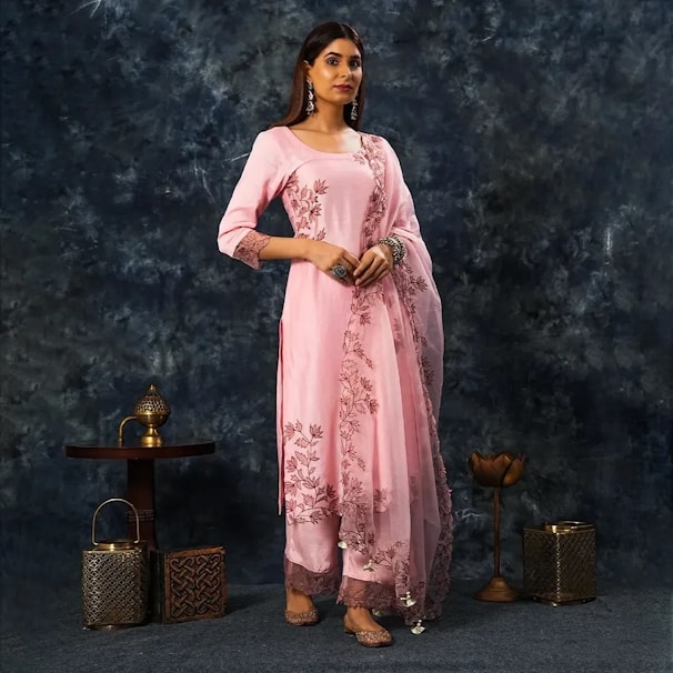 A woman in a pink outfit standing in front of a blue background
