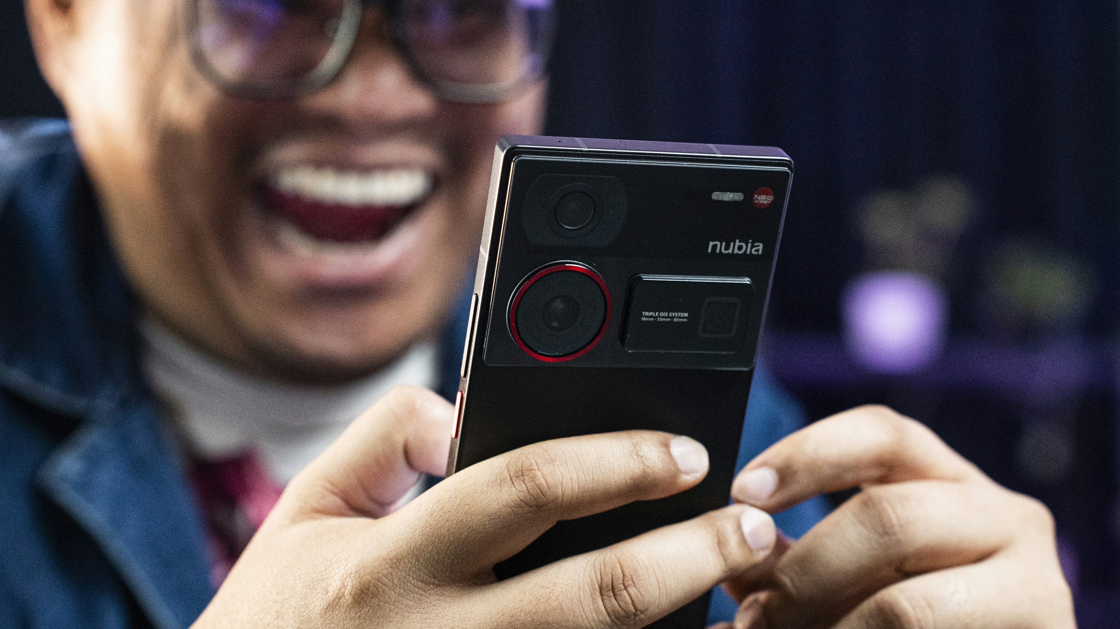 A man laughing while holding a cell phone