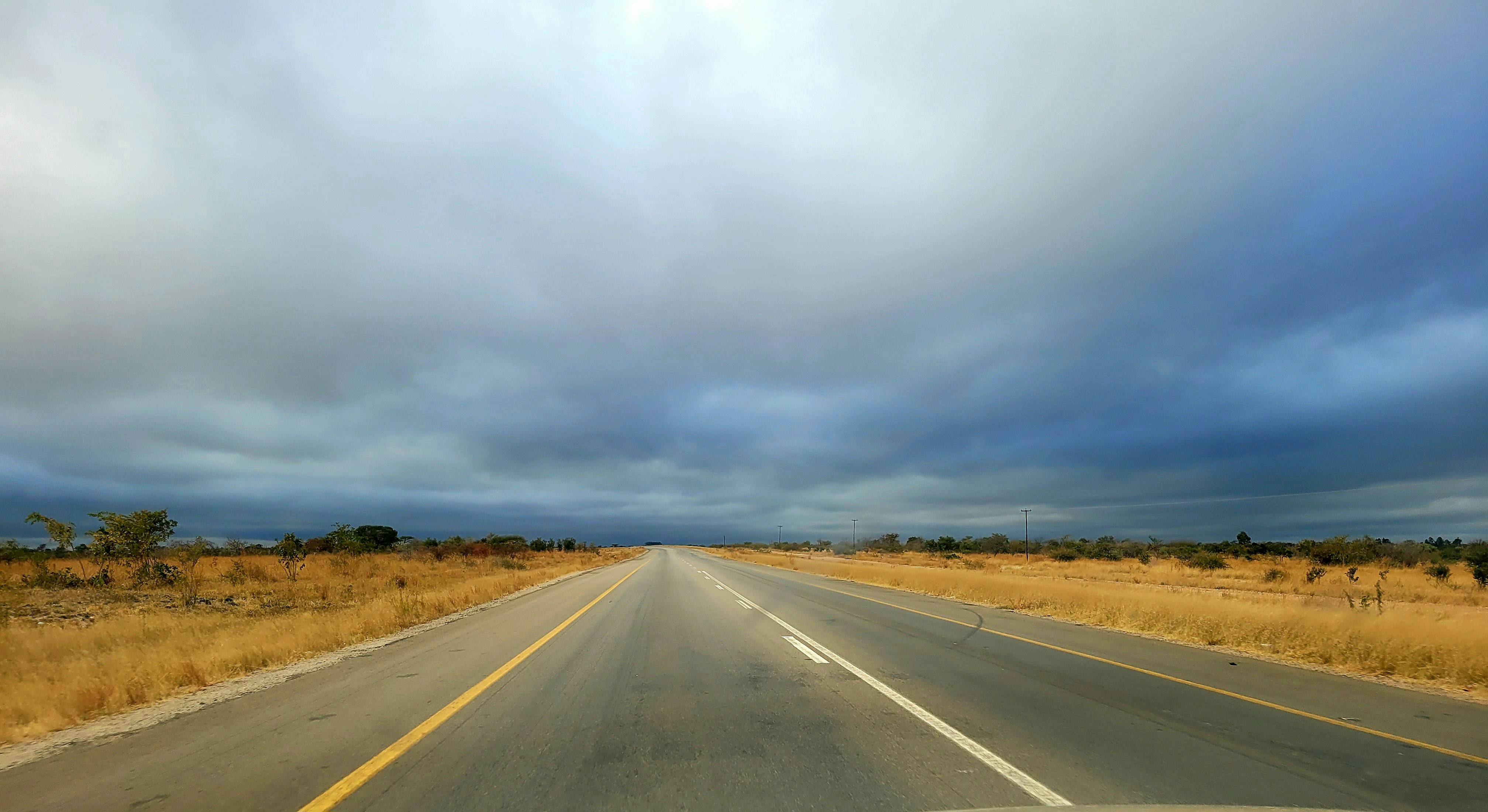 A car driving down a road under a cloudy sky