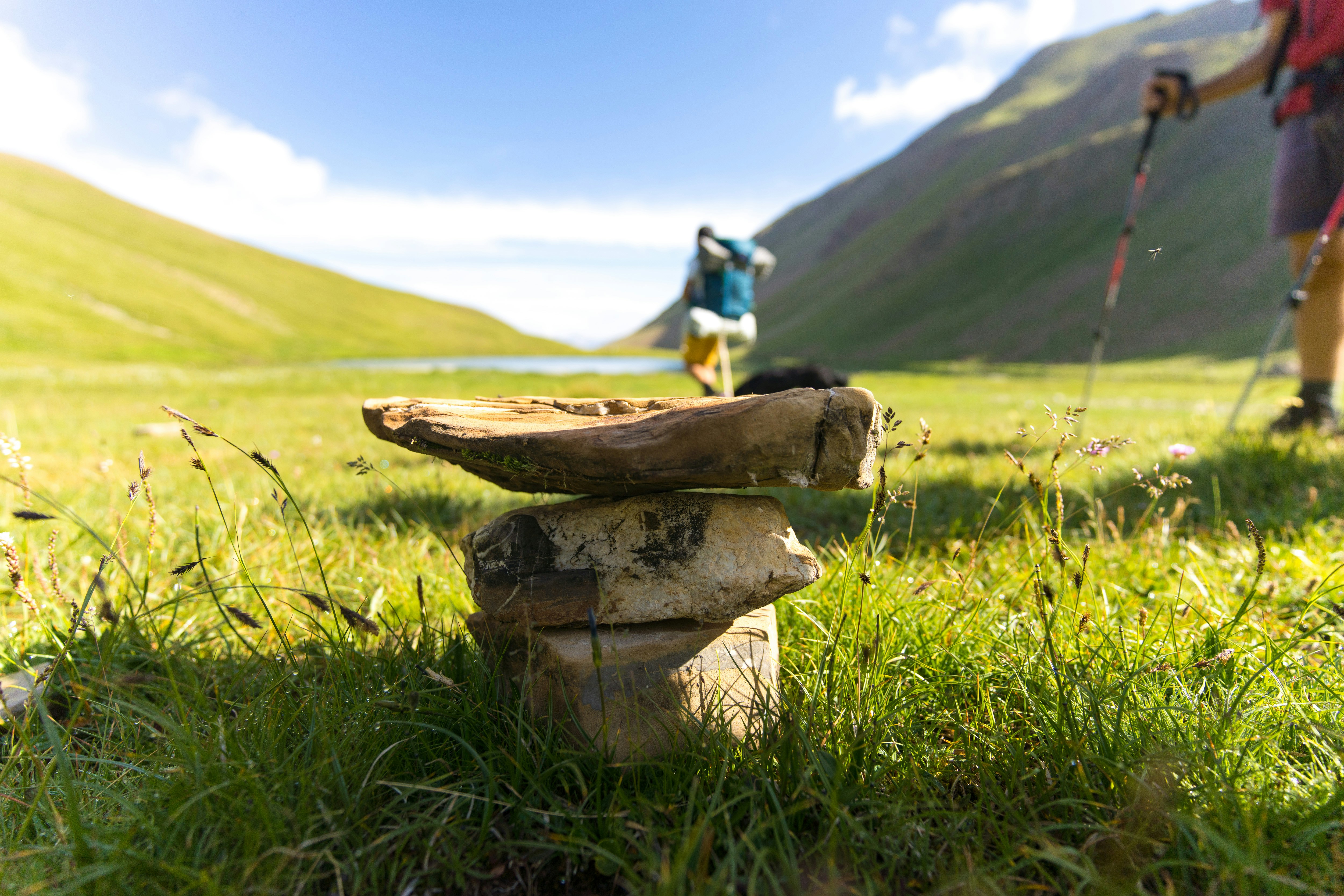 Stone cairn on a mountain trail with hikers.