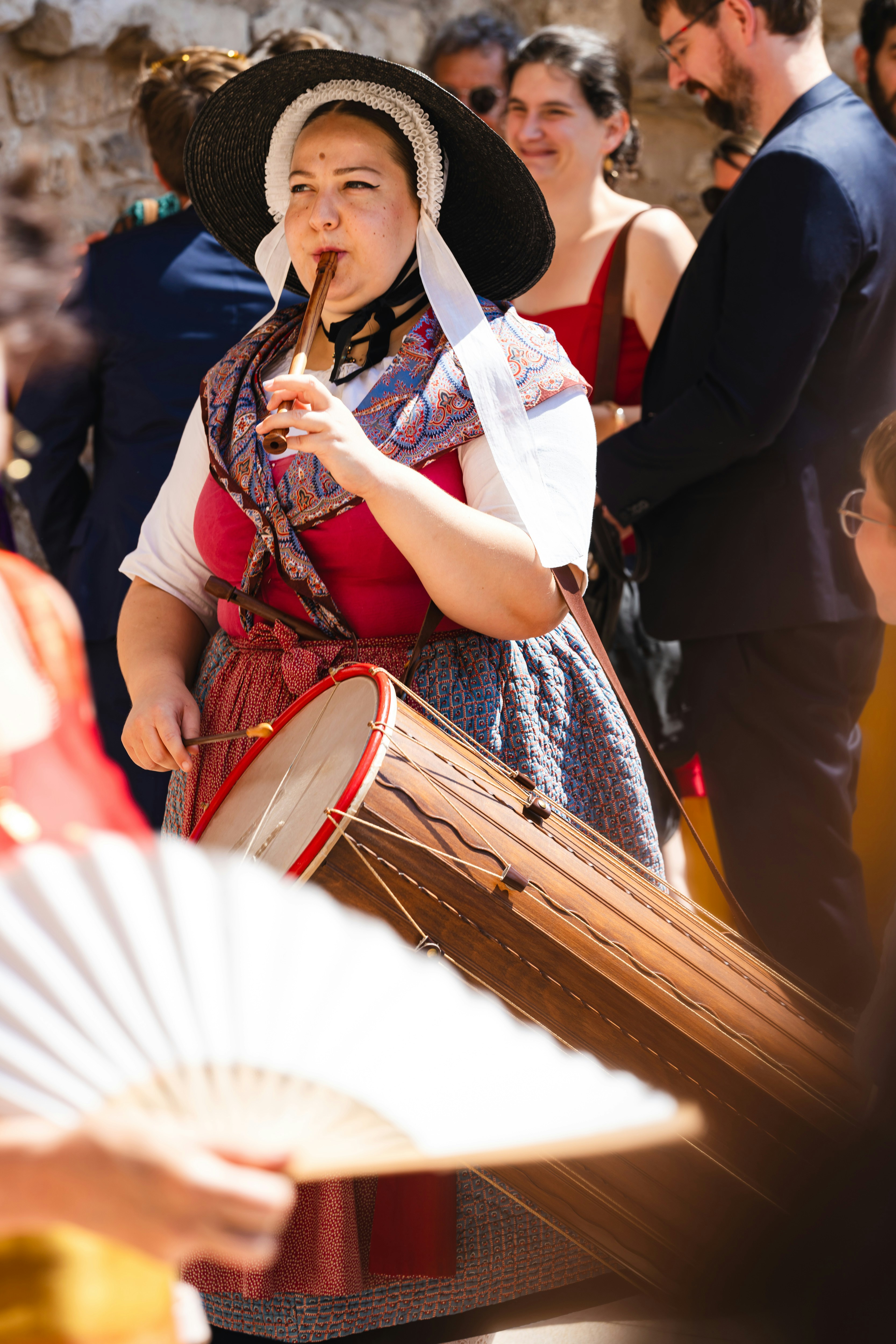 A woman wearing a hat and holding a fan