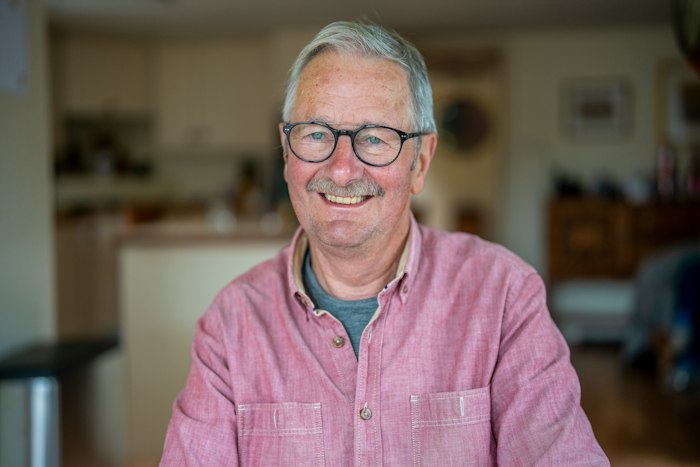 Jonas Reeve, stand-in portrait: a grey-haired man in glasses and a pink shirt, smiling