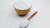 A wooden bowl and a wooden spoon filled with white powder