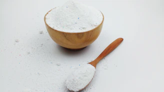 A wooden bowl and a wooden spoon filled with white powder