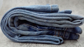 A pile of blue jeans sitting on top of a white floor
