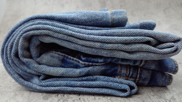 A pile of blue jeans sitting on top of a white floor