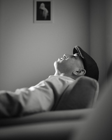 A black and white photo of a man laying on a couch