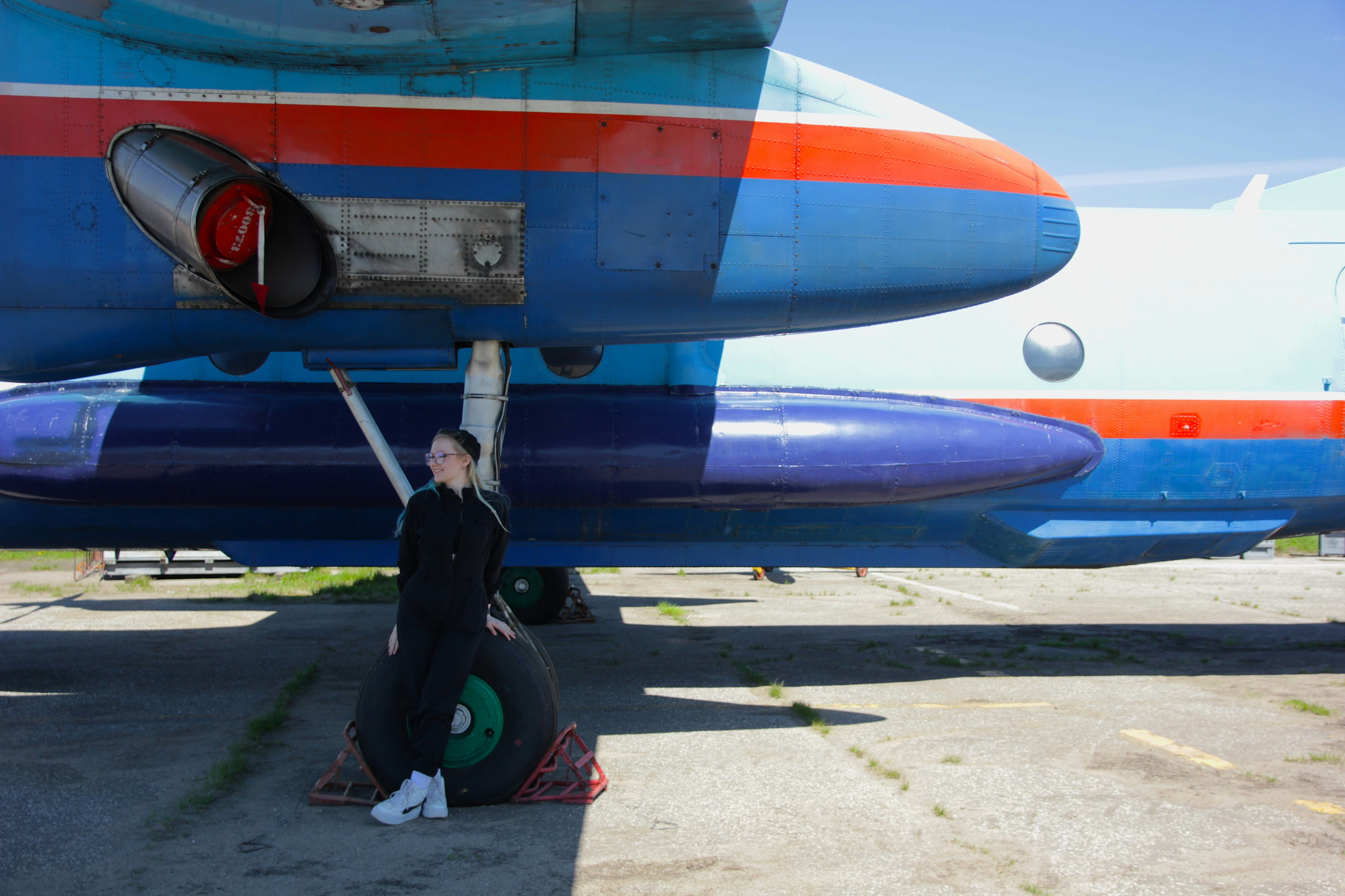 A man sitting on the ground in front of an airplane, feel