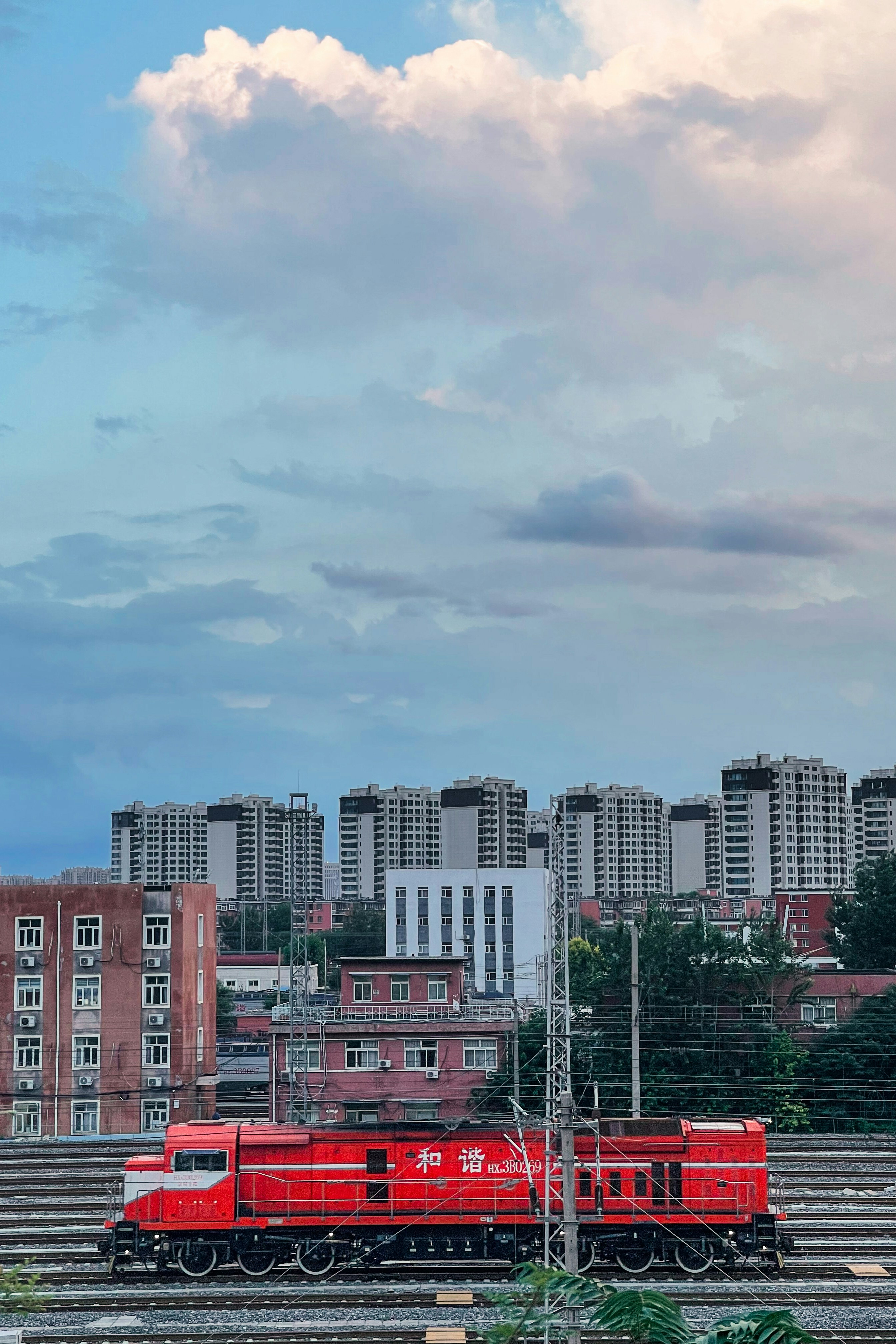 A red train traveling down train tracks next to tall buildings