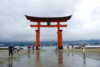 A group of people walking under a large red gate