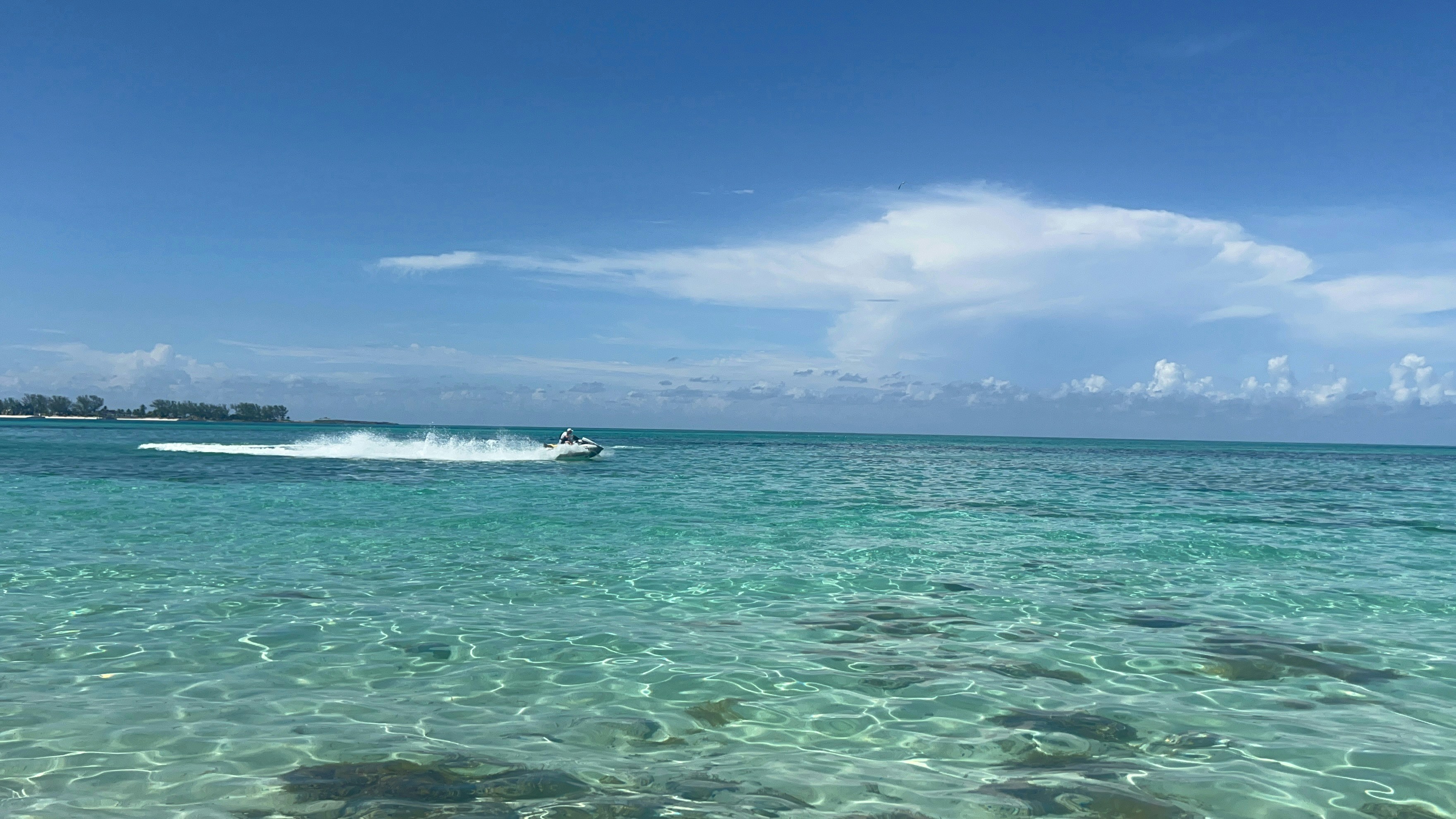 Jetski voznik hitro vozi po turkiznih vodah Dubaja z Burj Al Arab v ozadju