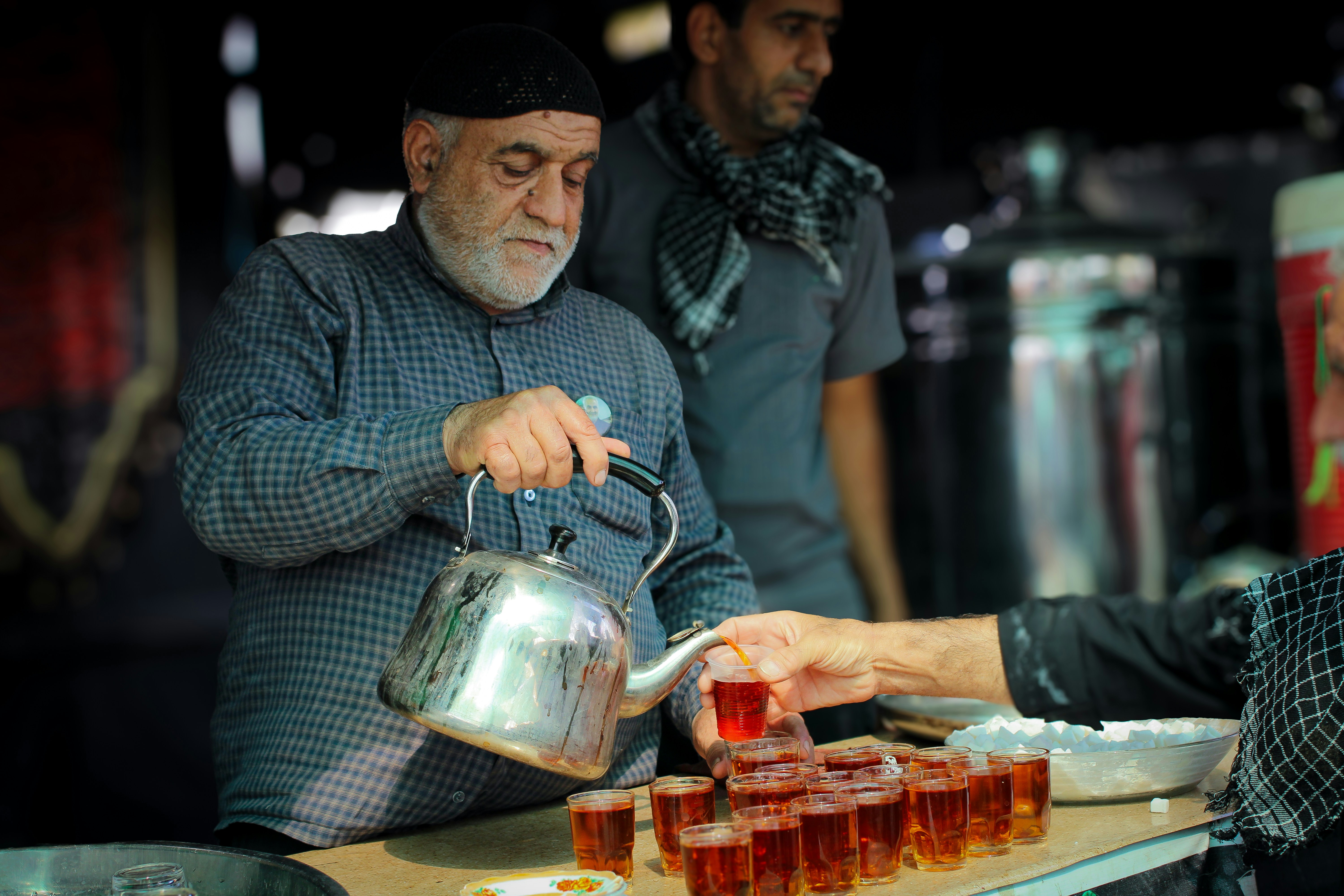 Un homme verse du thé dans une casserole pendant qu’un autre homme regarde