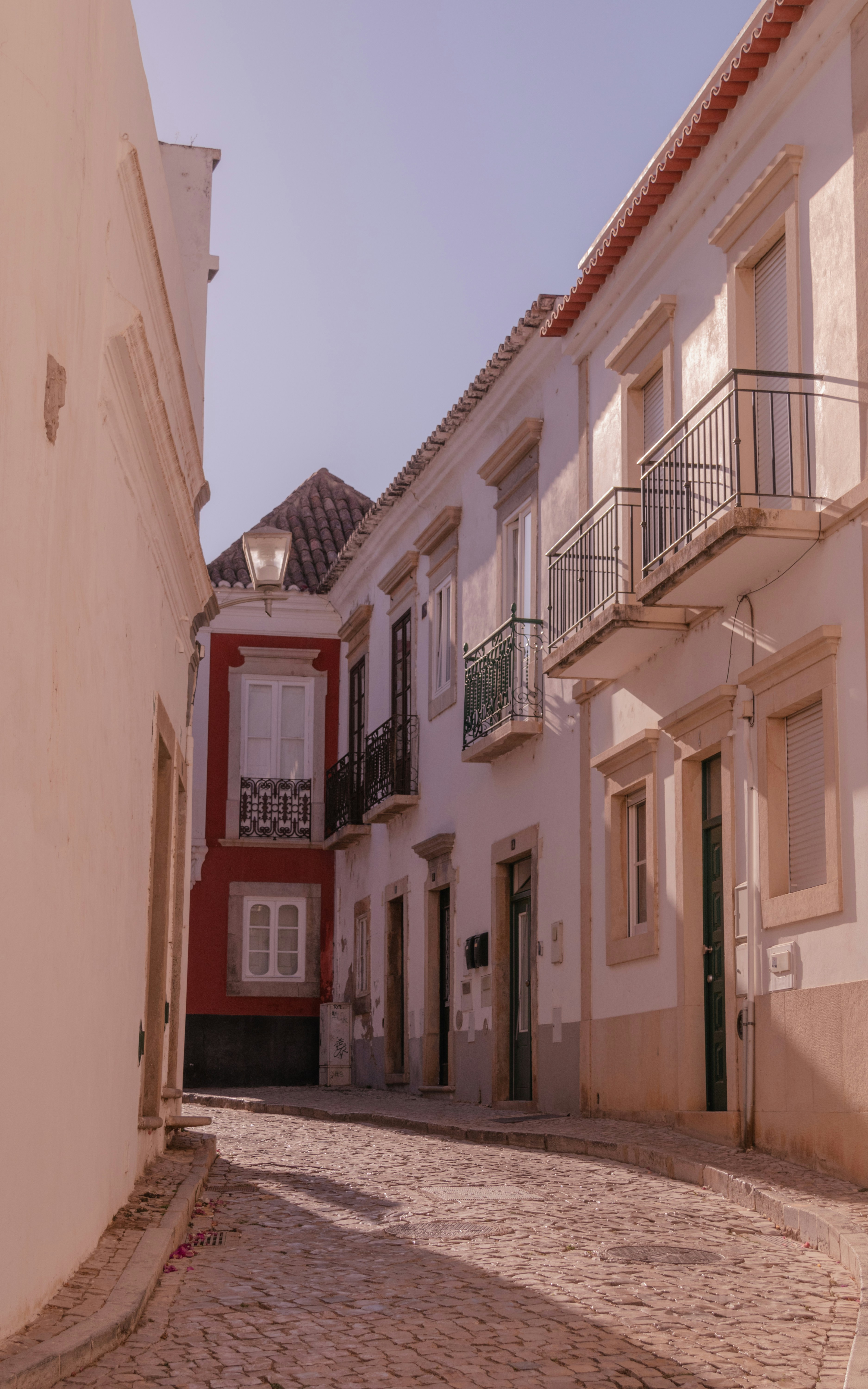 A cobblestone street lined with white buildings