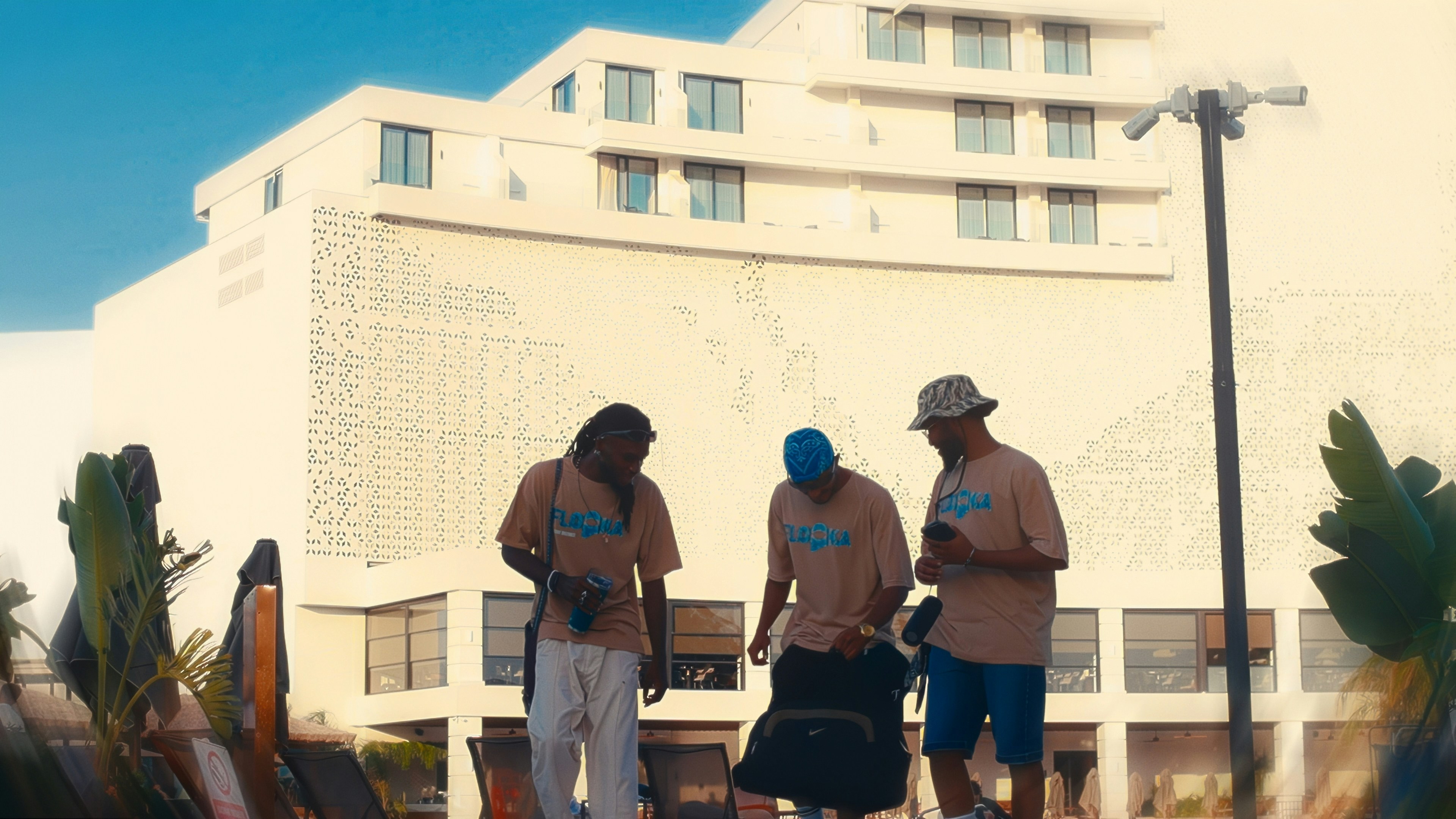 A group of men walking down a street next to a tall building