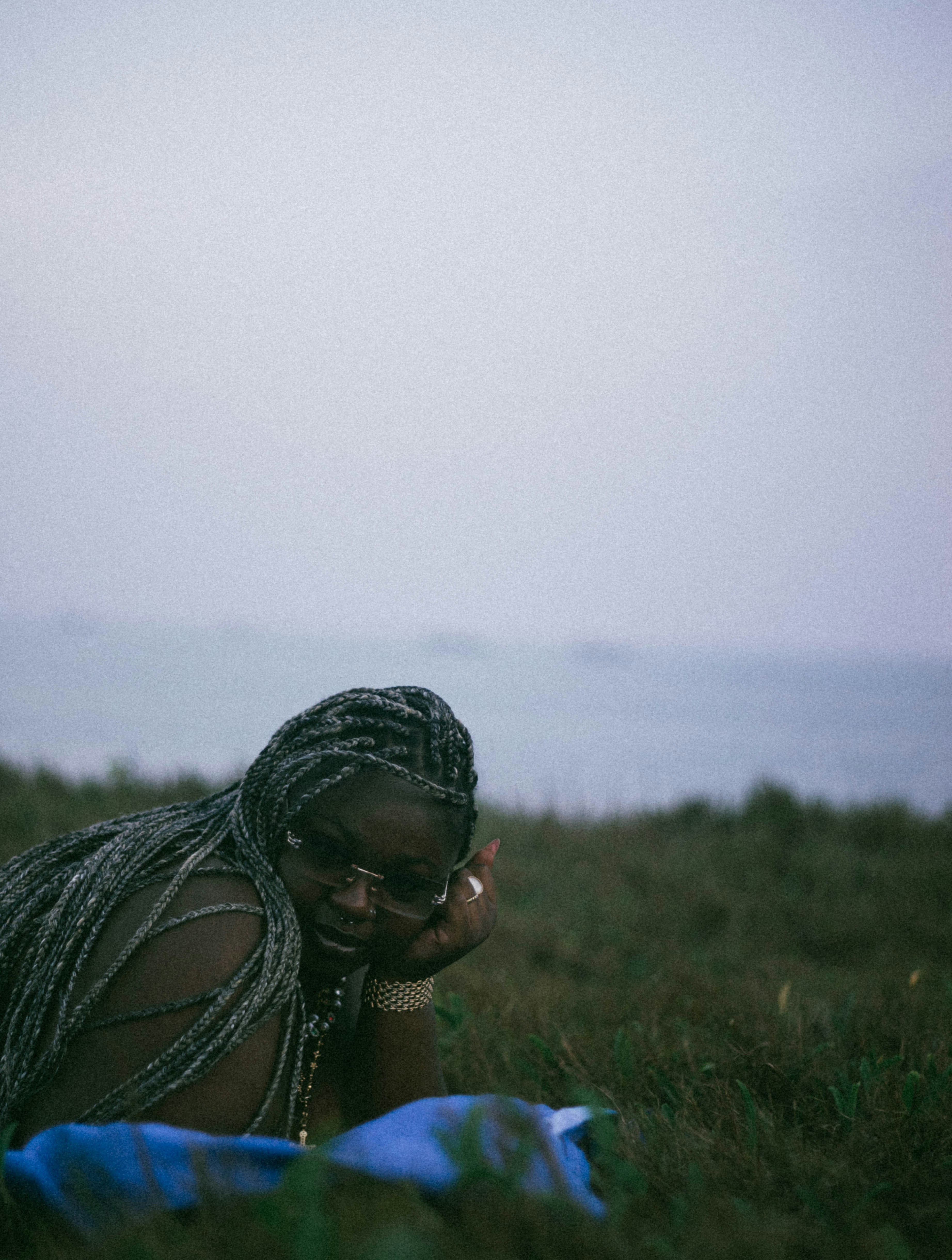 A woman laying in the grass talking on a cell phone