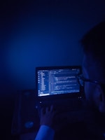 A man sitting in front of a laptop computer in a dark room