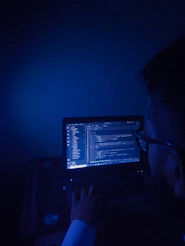 A man sitting in front of a laptop computer in a dark room
