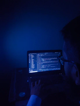 A man sitting in front of a laptop computer in a dark room