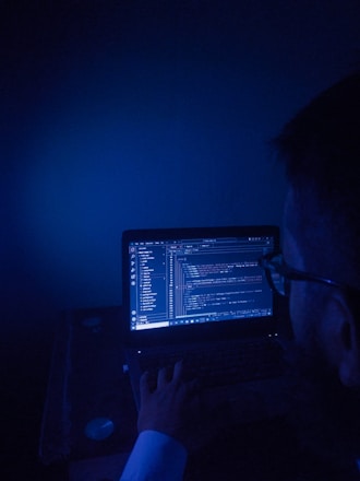A man sitting in front of a laptop computer in a dark room