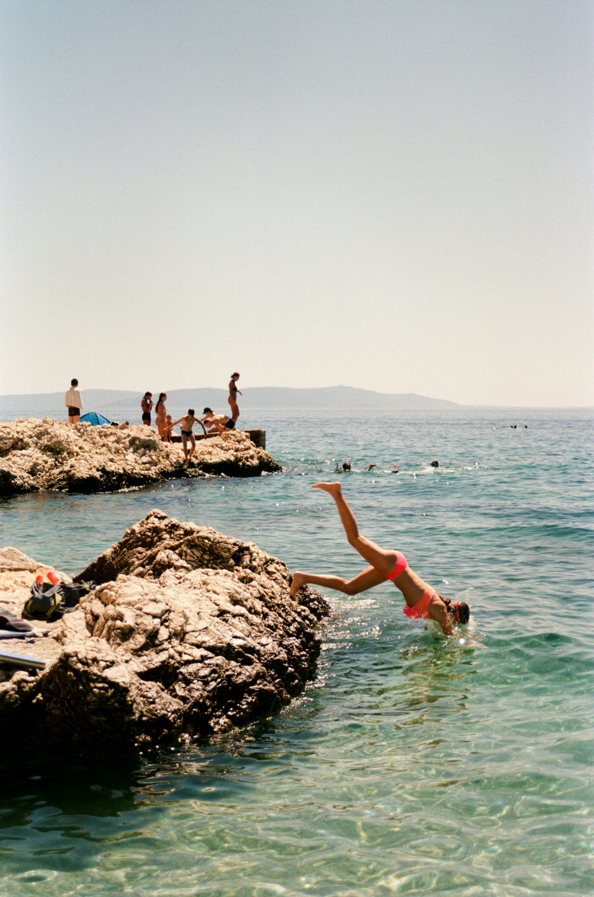 A man diving into the ocean from a rocky cliff