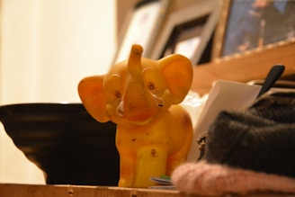 A yellow elephant figurine sitting on top of a desk