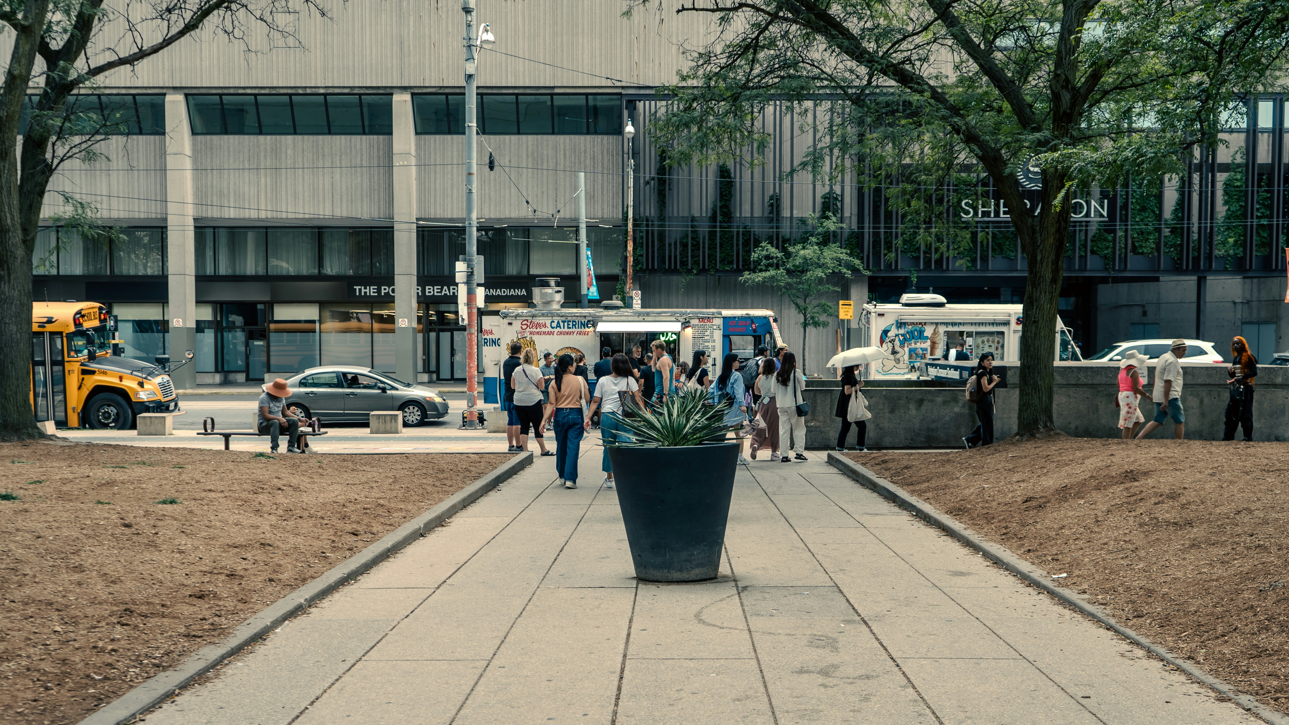 A group of people walking down a sidewalk next to a tall building