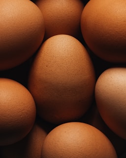 A pile of brown eggs sitting on top of each other