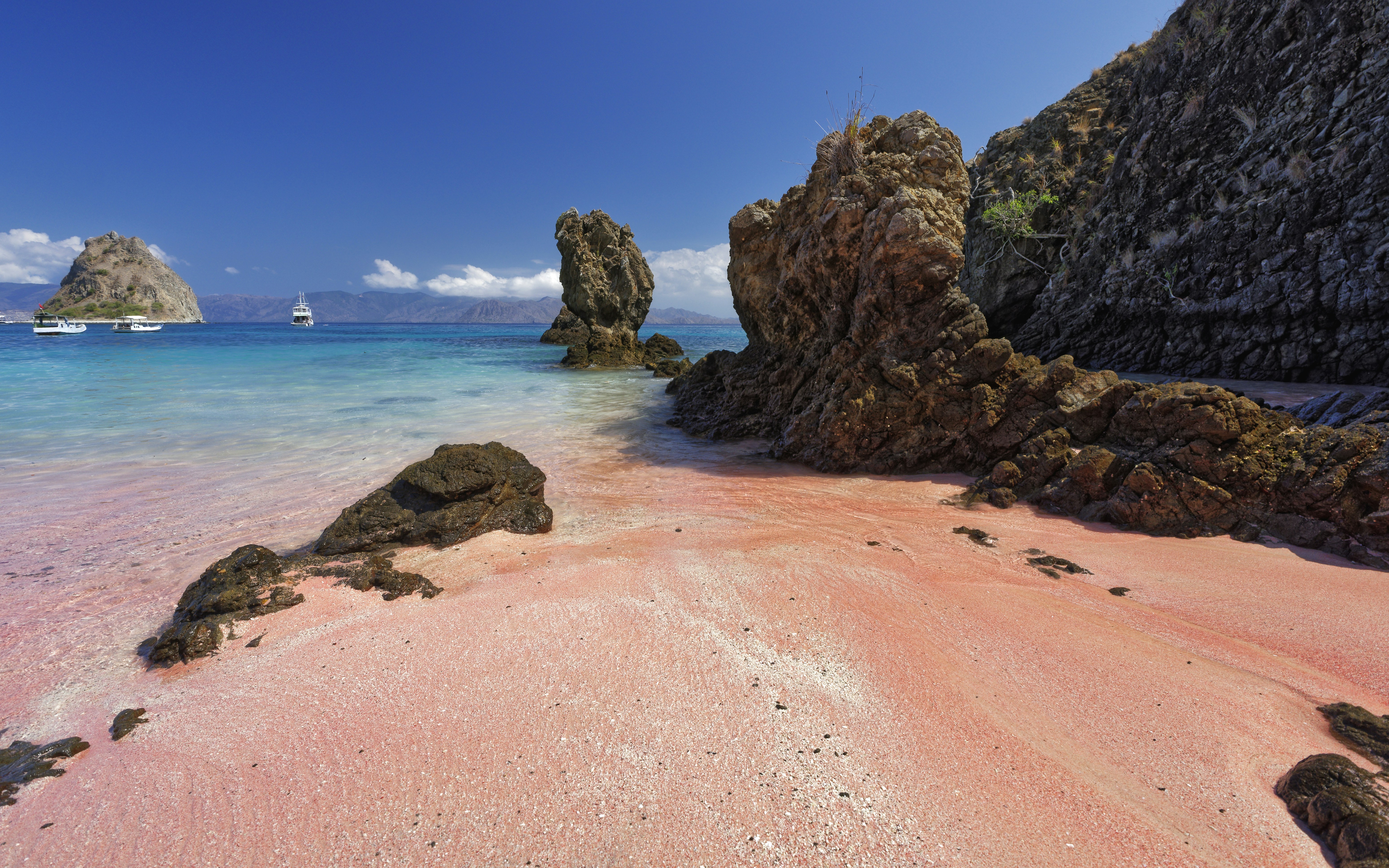 A sandy beach with a rock formation in the water