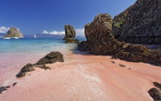 A sandy beach with a rock formation in the water