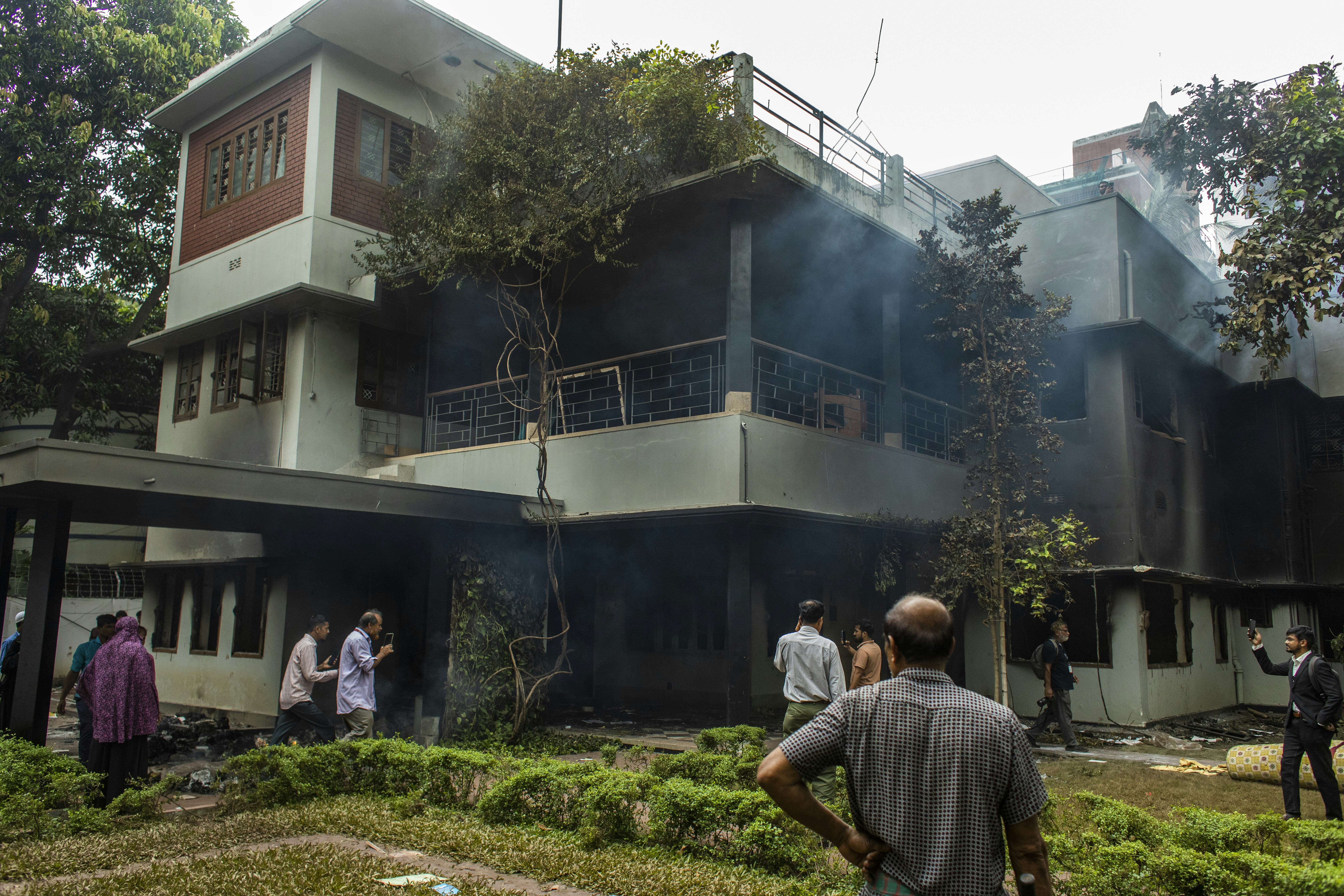 Fire damaged building exterior with charred walls and broken windows, dark smoke staining visible on structure