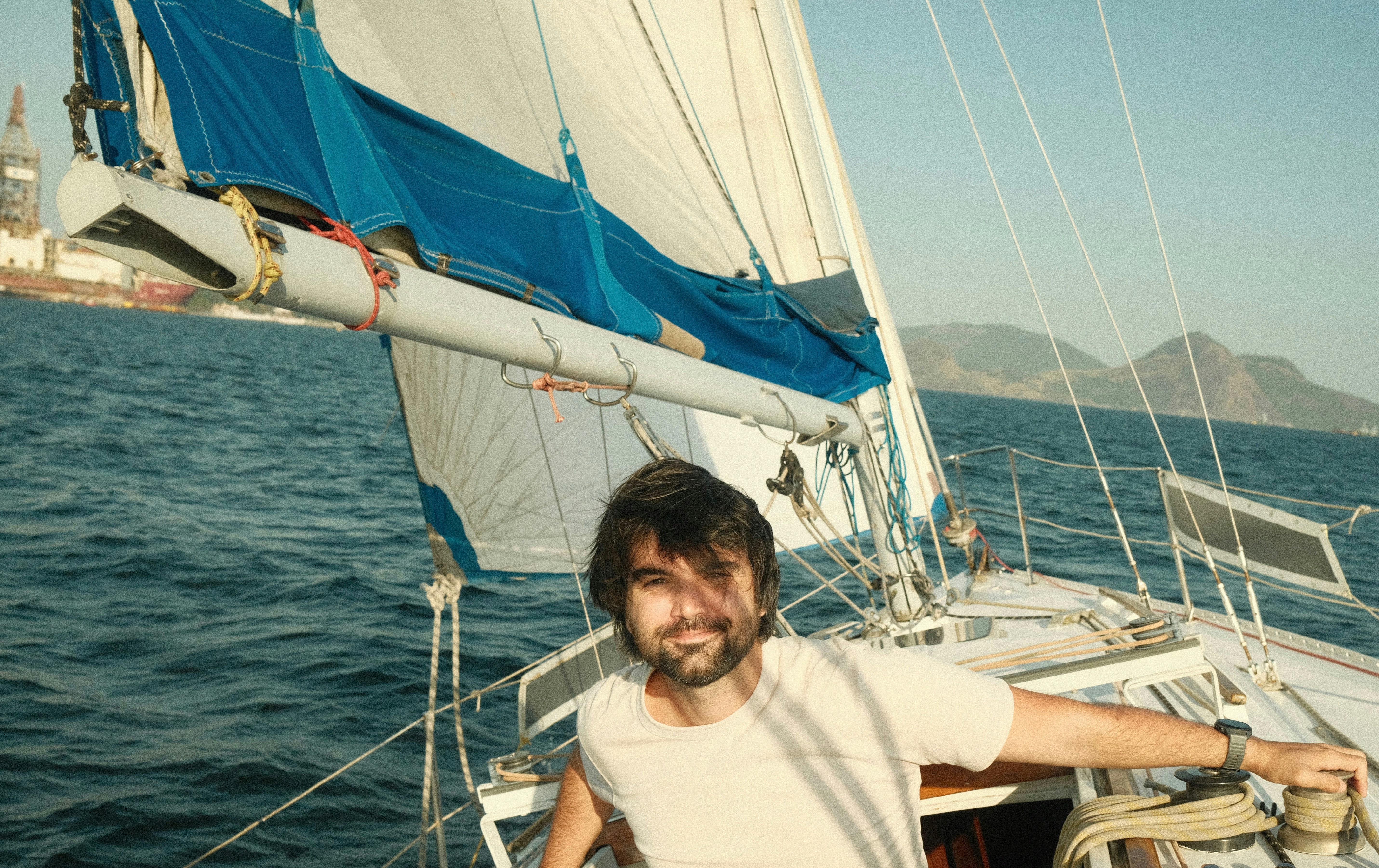 A man standing on a sailboat in the ocean