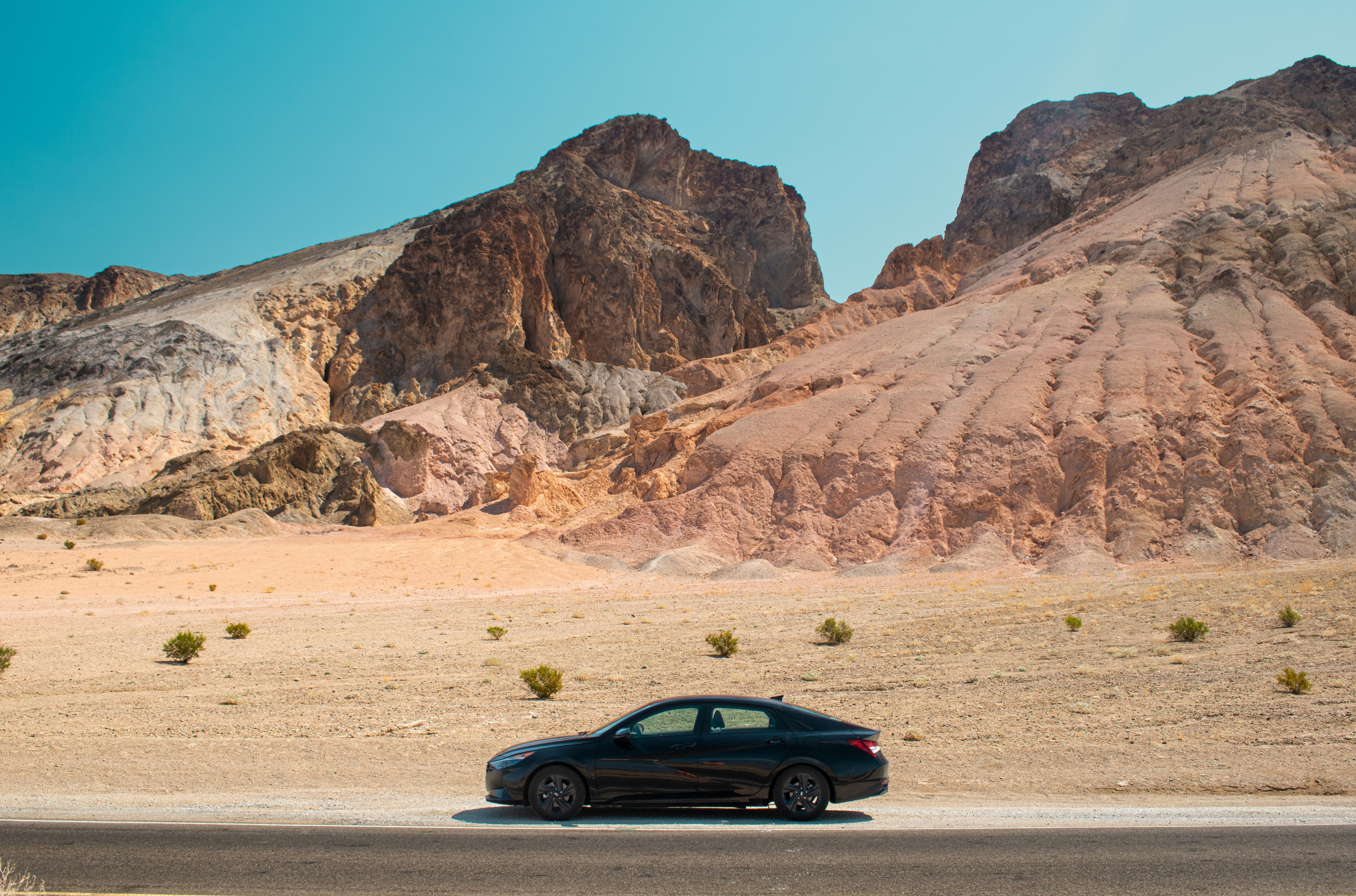 black sedan parked in front of desert mountains