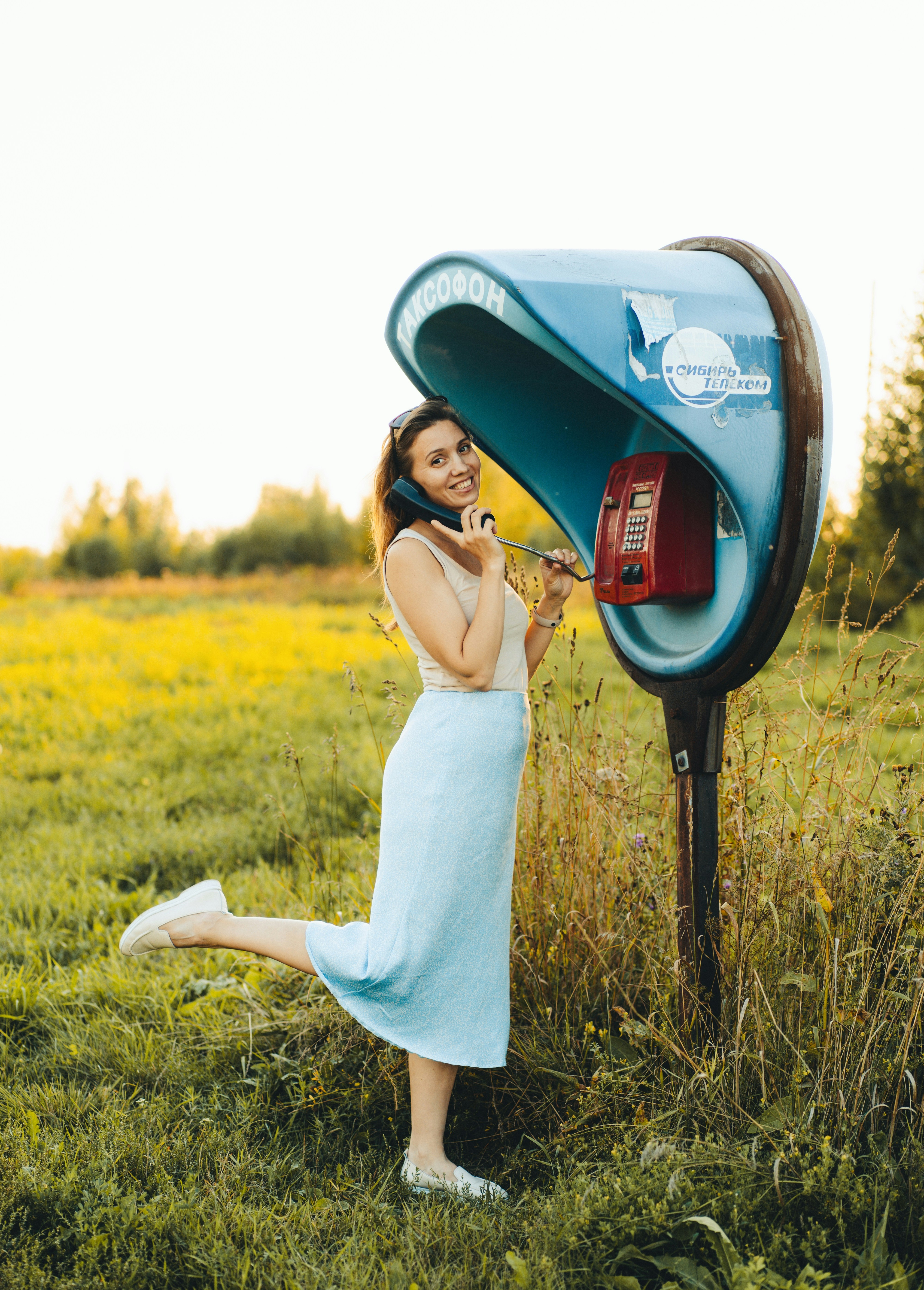 A woman in a blue dress talking on a cell phone