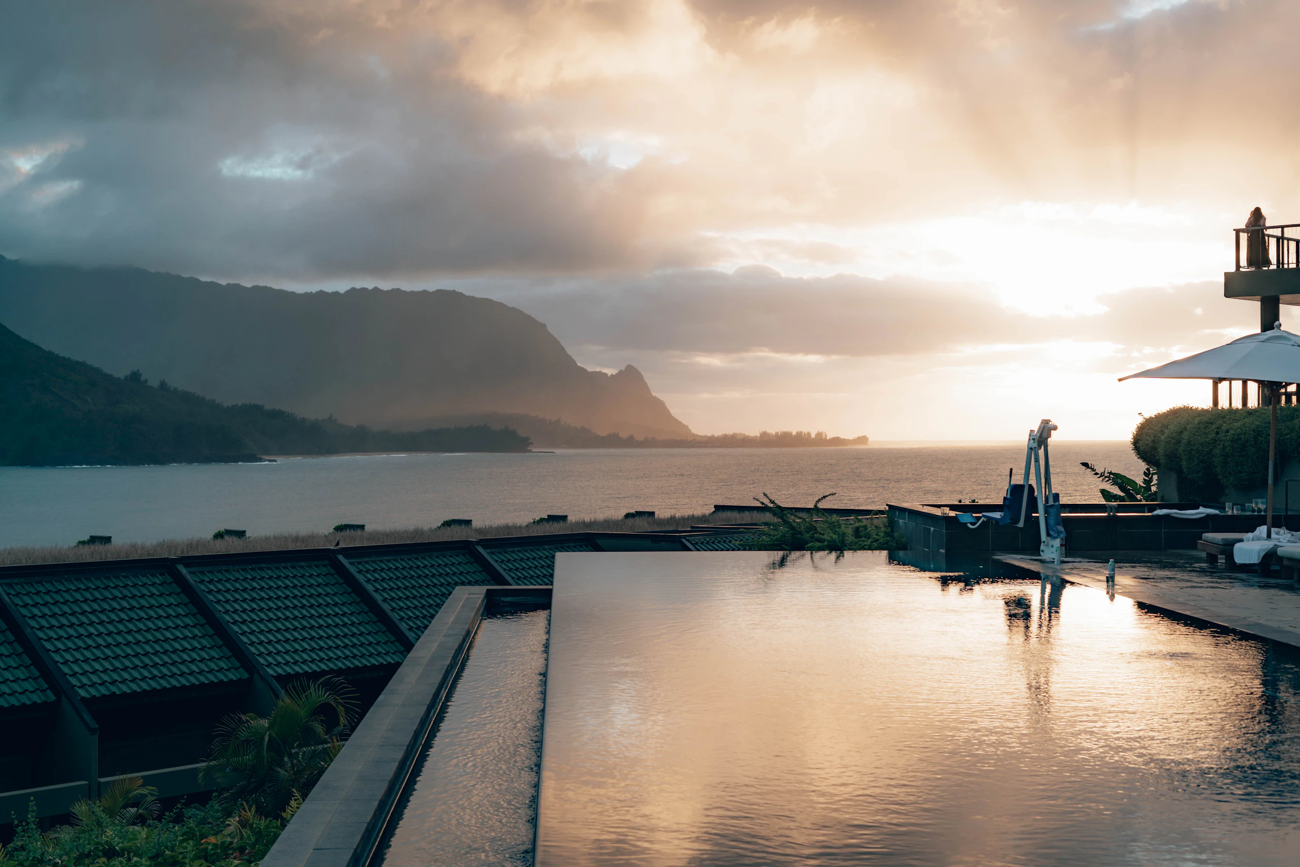 Swimming pool beside the water with green mountains behind