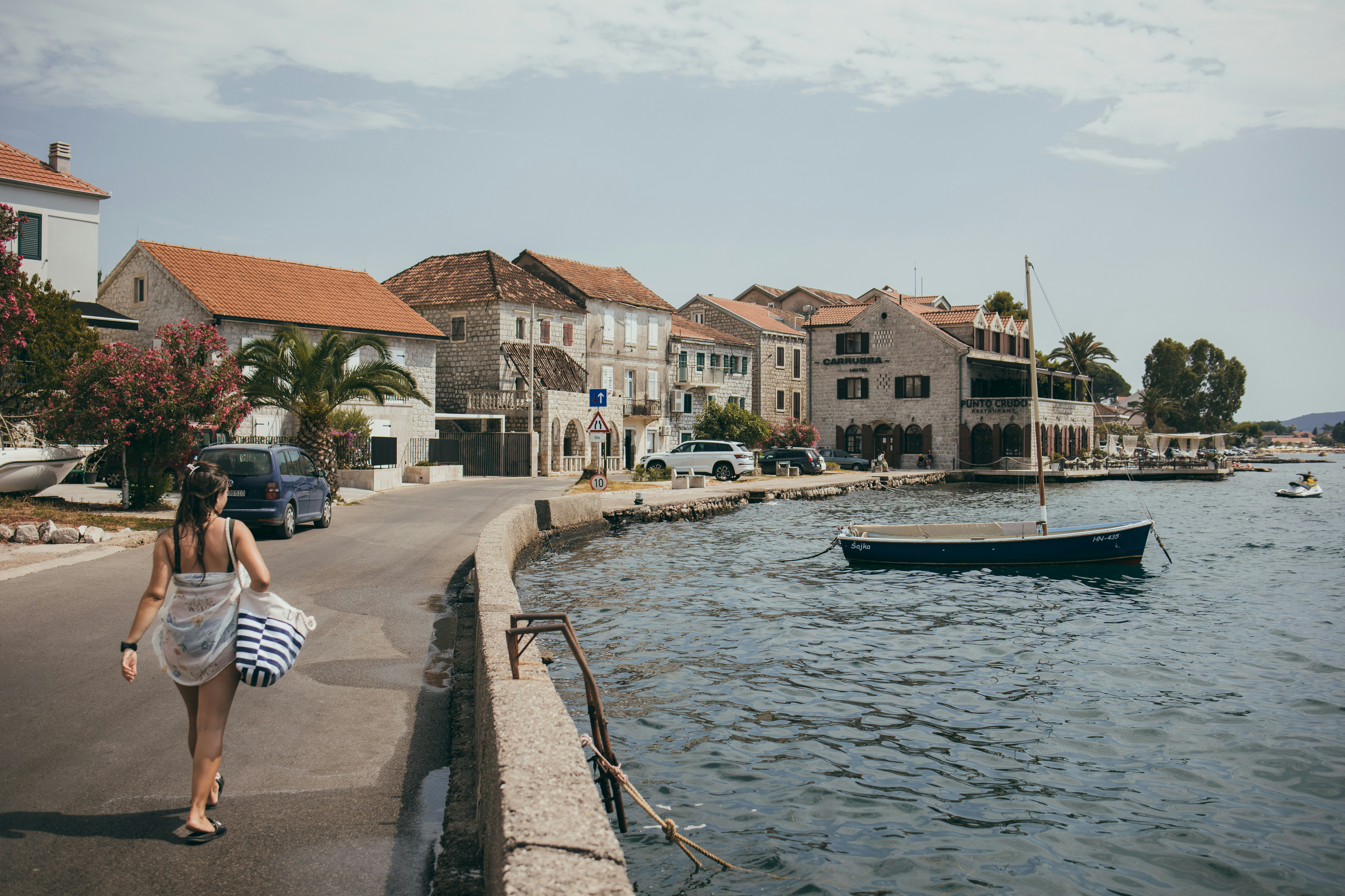 A woman walking down a street next to a body of water