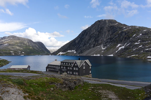 A house sitting on the side of a mountain next to a lake