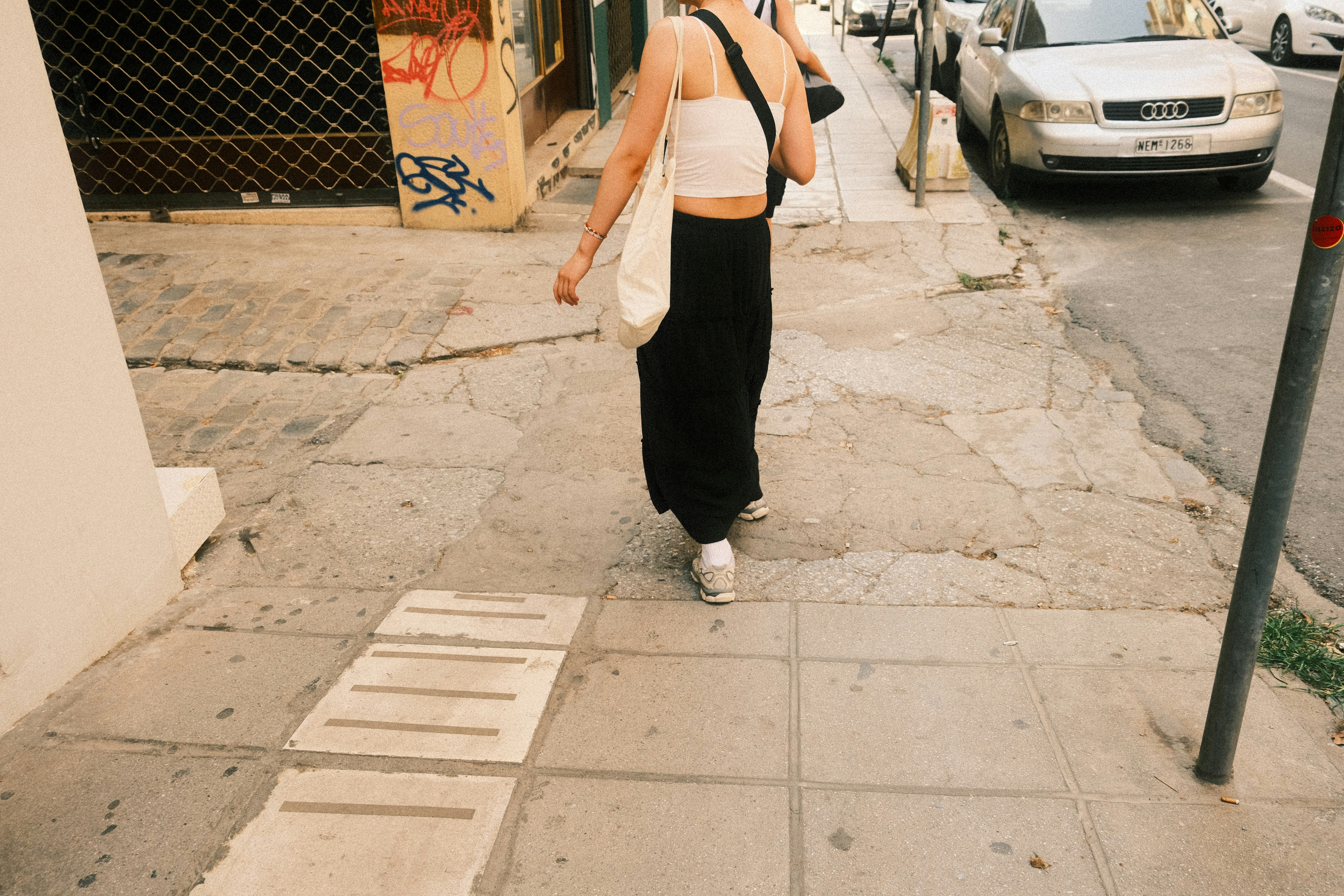 A woman walking down a sidewalk talking on a cell phone