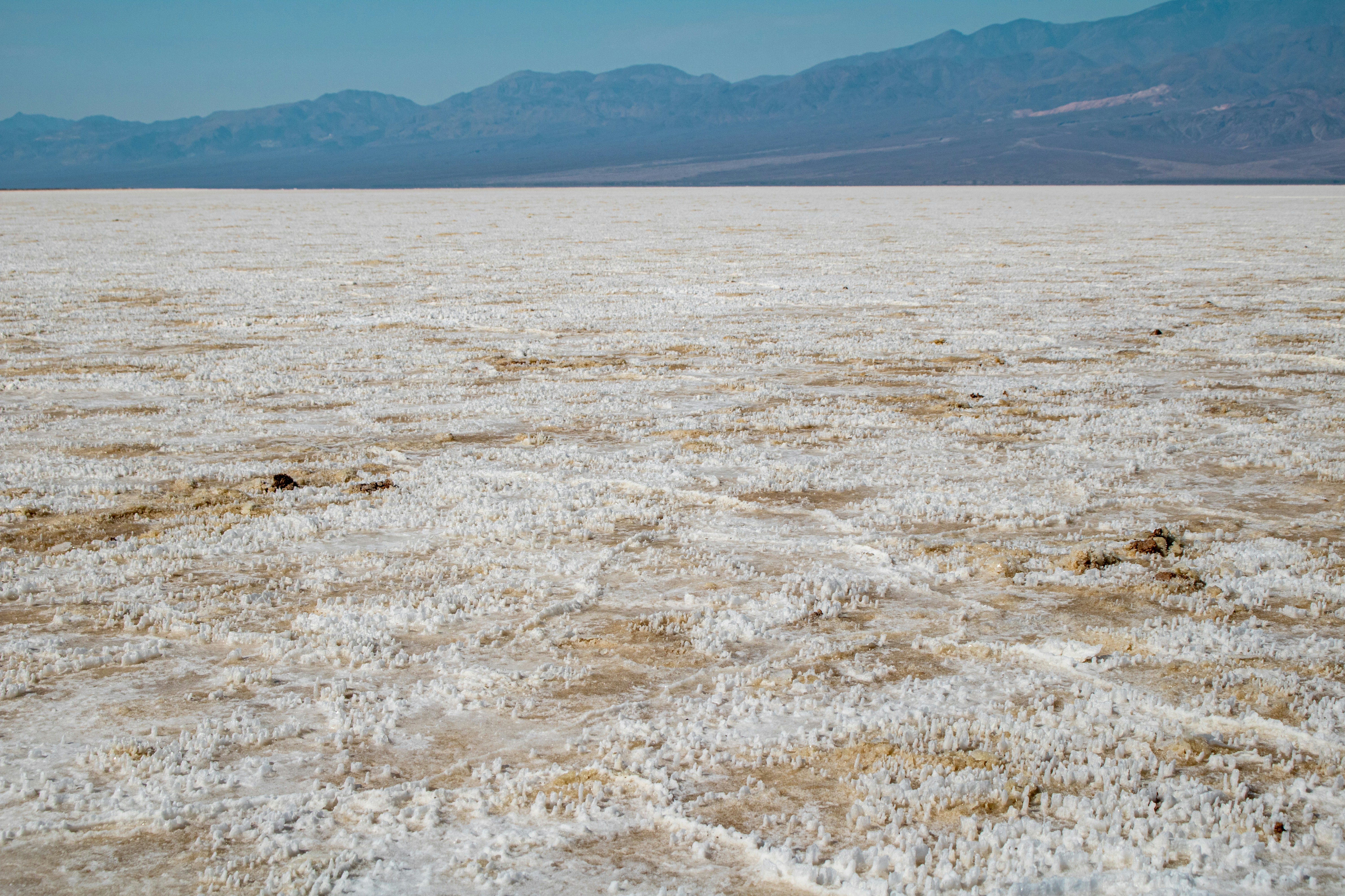 Badwater Basin, located in Death Valley National Park, is one of the most iconic and extreme landscapes in the United States. It holds the record for the lowest point in North America at 282 feet (86 meters) below sea level. The basin is part of a vast, flat expanse of salt flats that stretch across the valley floor, creating a surreal and starkly beautiful environment. The salt flats are formed by the evaporation of ancient lakes, leaving behind vast deposits of sodium chloride. Over time, these deposits crystallize into intricate, geometric patterns on the surface.