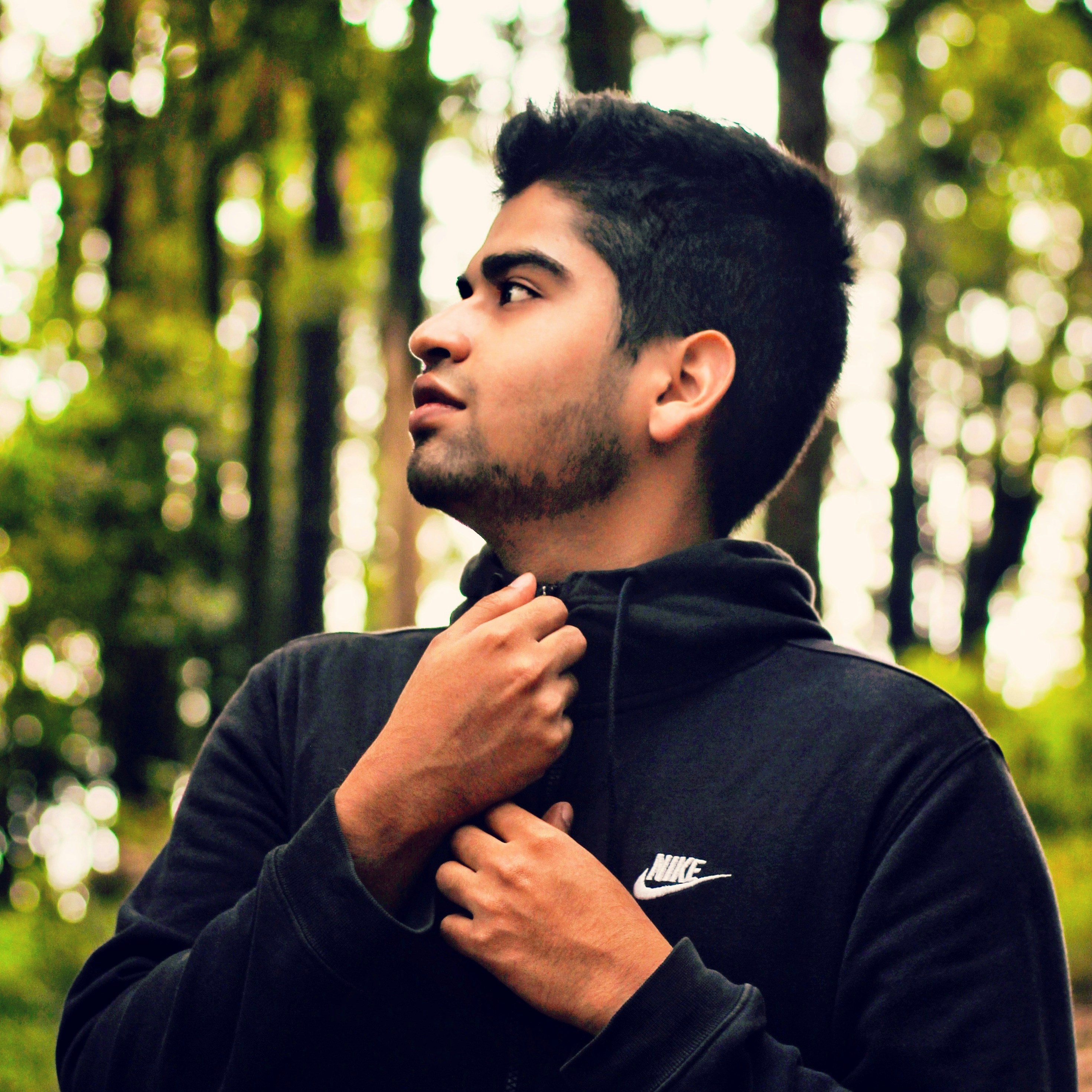 Un hombre con una sudadera negra con capucha de pie en un bosque