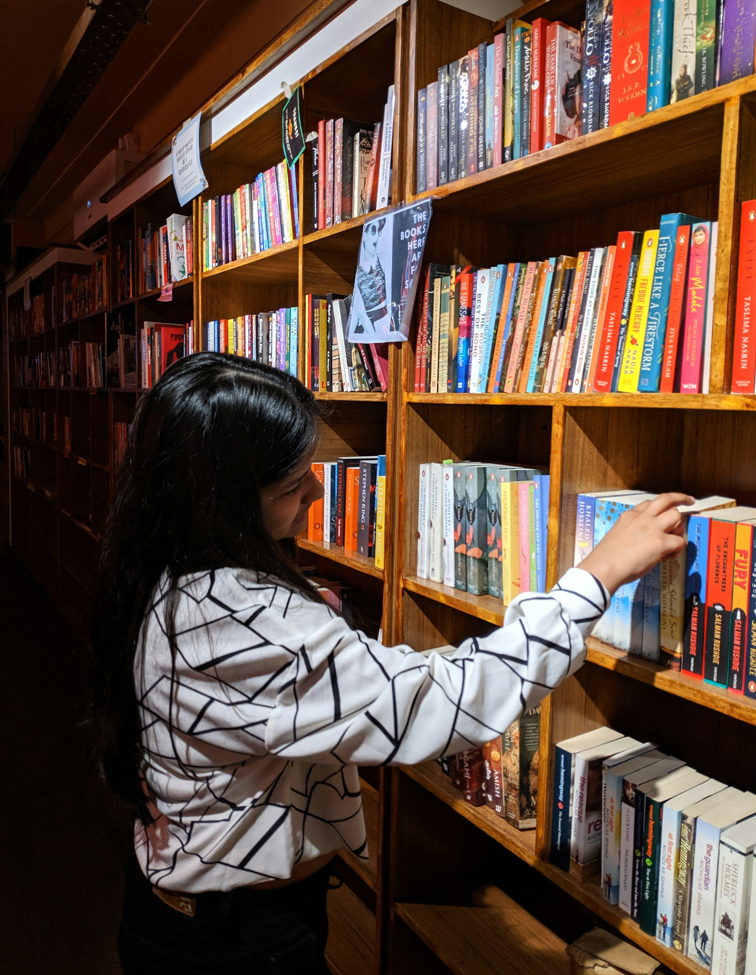 Una mujer mirando libros en una estantería